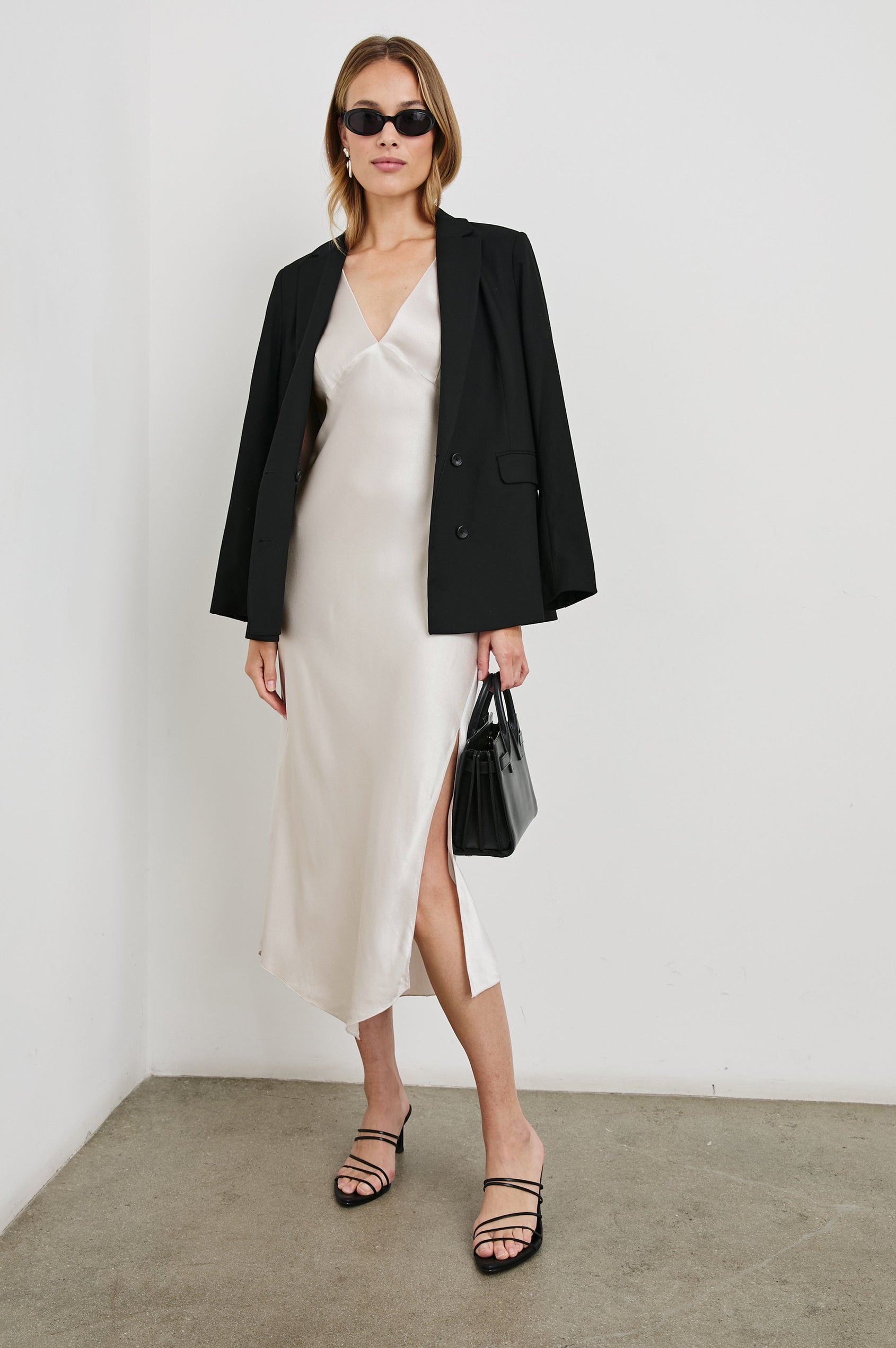 Monique Sleeveless Midi Dress with an Asymmetrical Hem Line, Side Slit, Deep V Neck, and Wide Shoulder Straps in Ivory Colorway - Front Full Body View Featured on Model