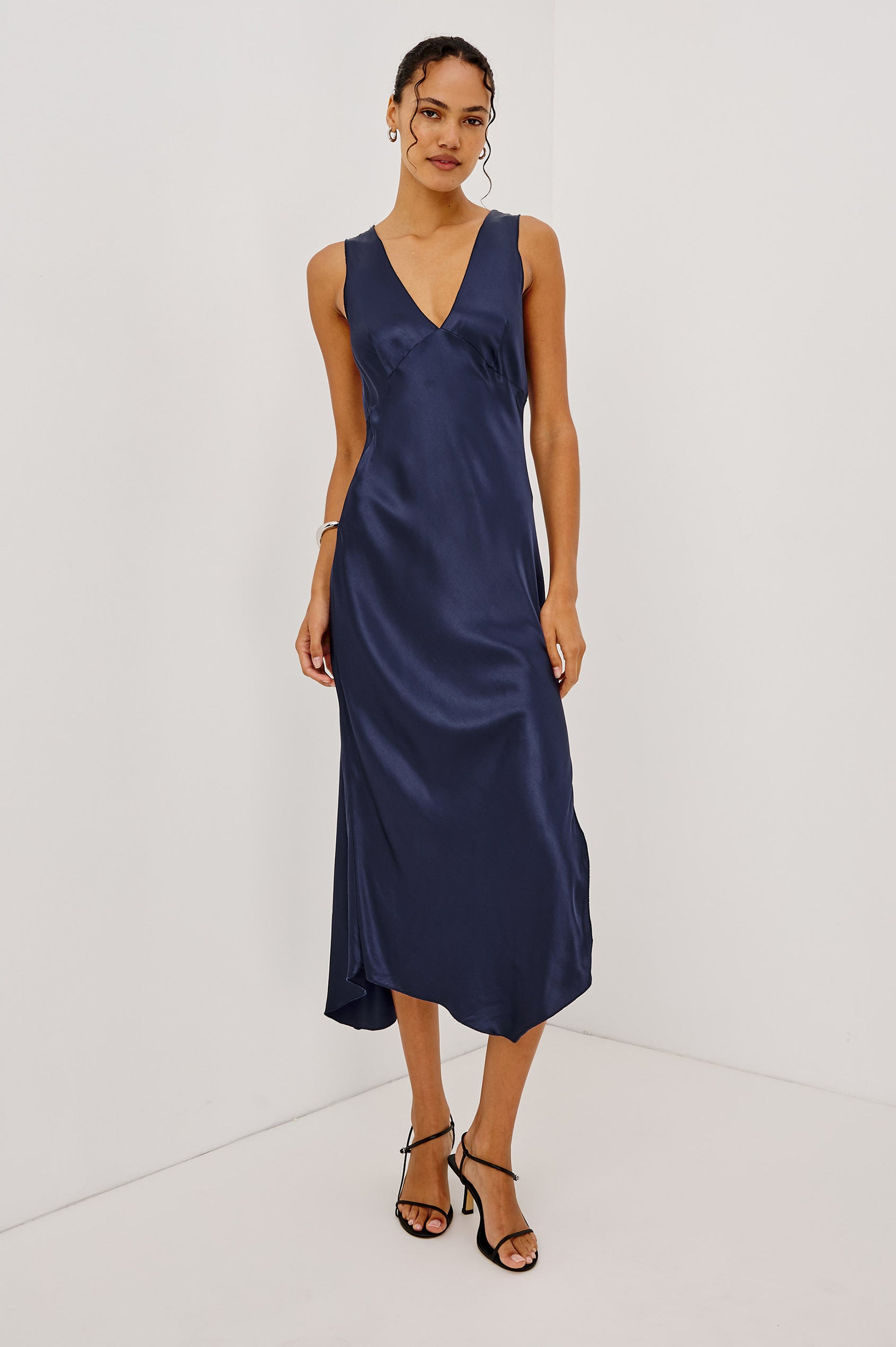 Monique Midi Bias Cut Slip Dress in Satin-Back Crepe With V-Neckline, Asymmetric Hem, and Side Slit in Navy Colorway - Full Body Front View Featured on Model