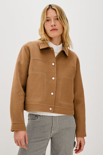 The Mountain jacket is cropped and collared with a snap front and side pockets in Camel colorway. Front view featured on model.