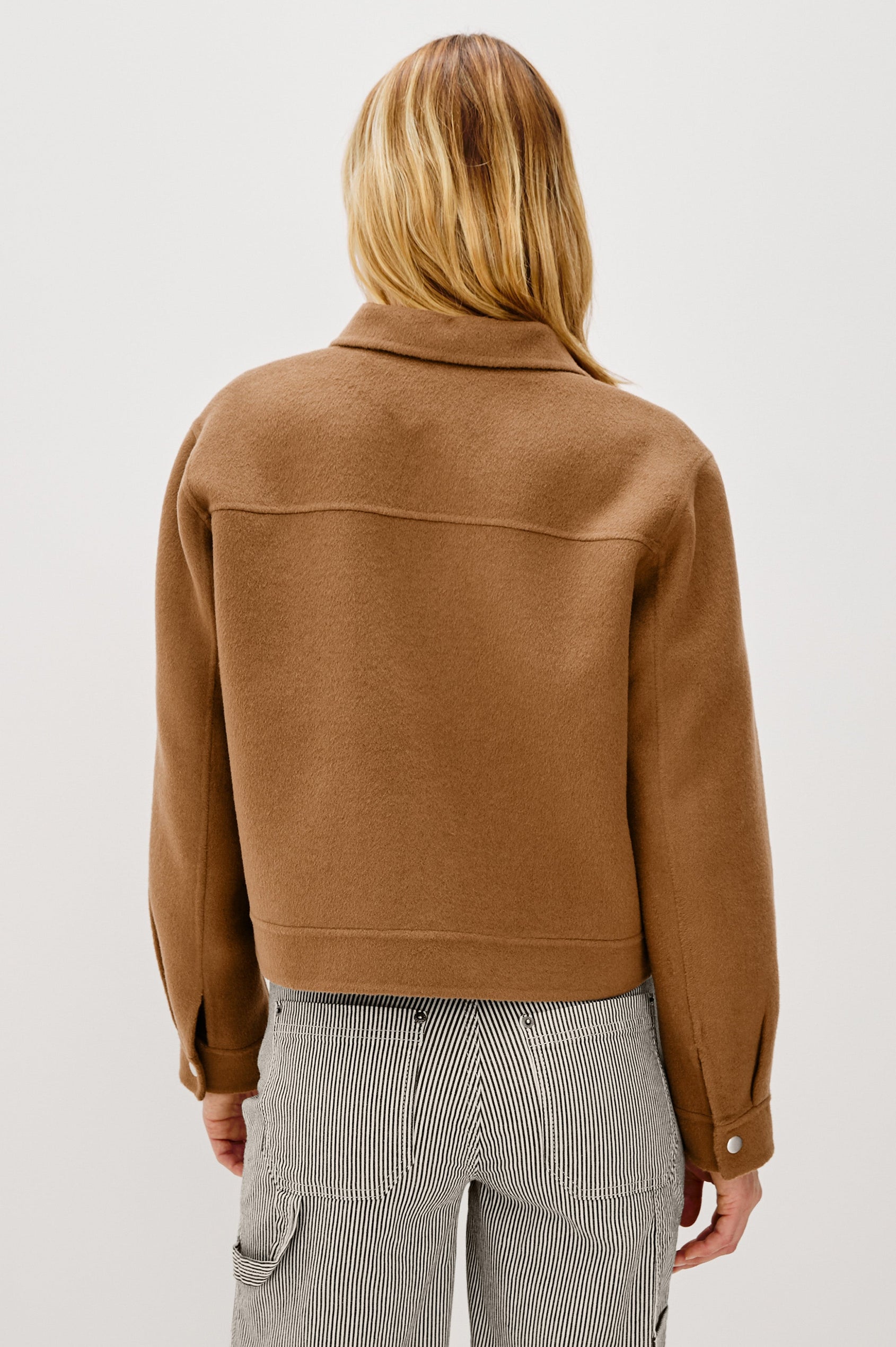 The Mountain jacket is cropped and collared with a snap front and side pockets in Camel colorway. Back view featured on model.