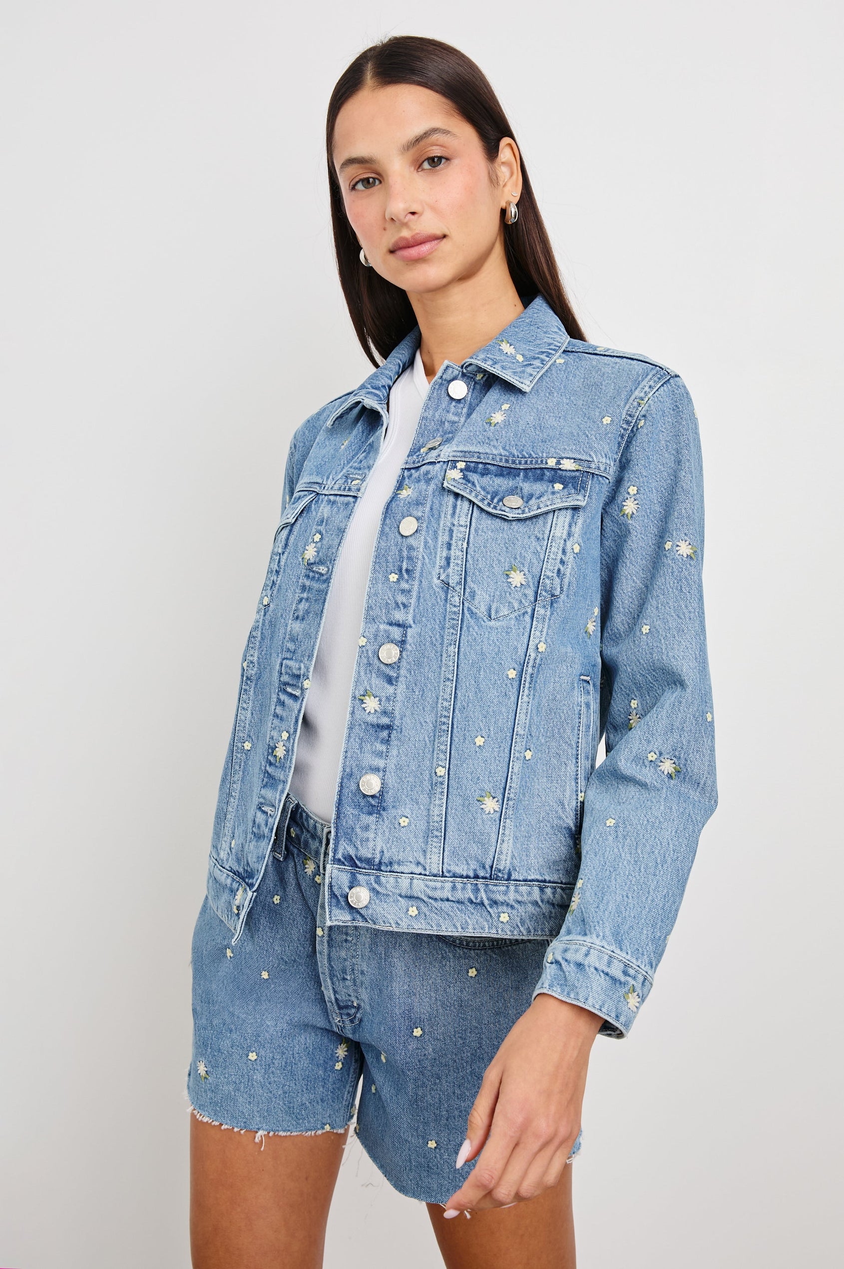 Mulholland Indigo Trucker Style Denim Jacket with 2 Front Pockets, Front Buttons, and Daisy Embroidery Details - Front View On Model at a Slight Angle