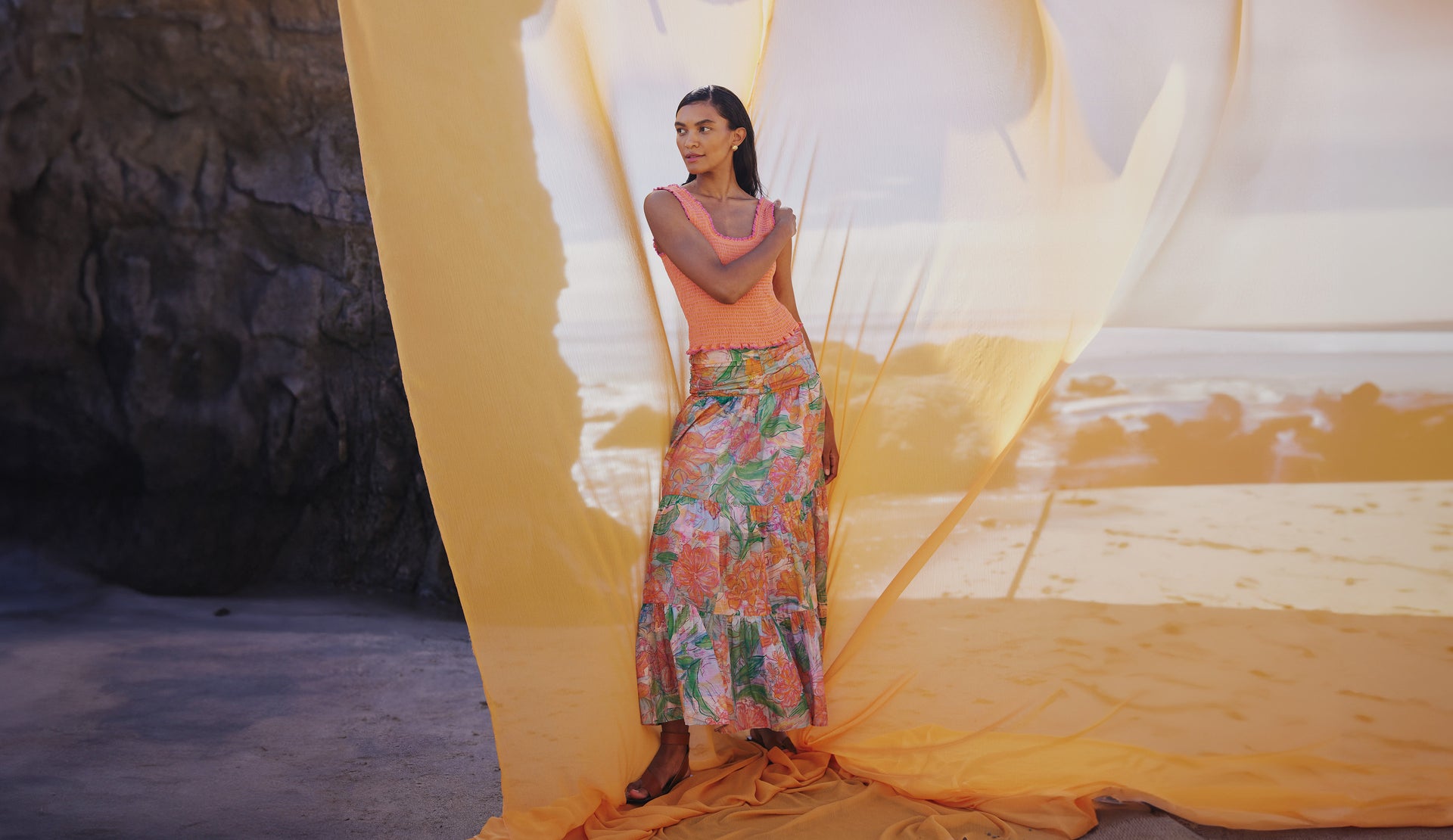 FRONT FULL BODY EDITORIAL IMAGE OF MODEL ON THE BEACH WEARING MAXINE TOP IN PAPAYA AND AGATHA SKIRT IN TROPICS
