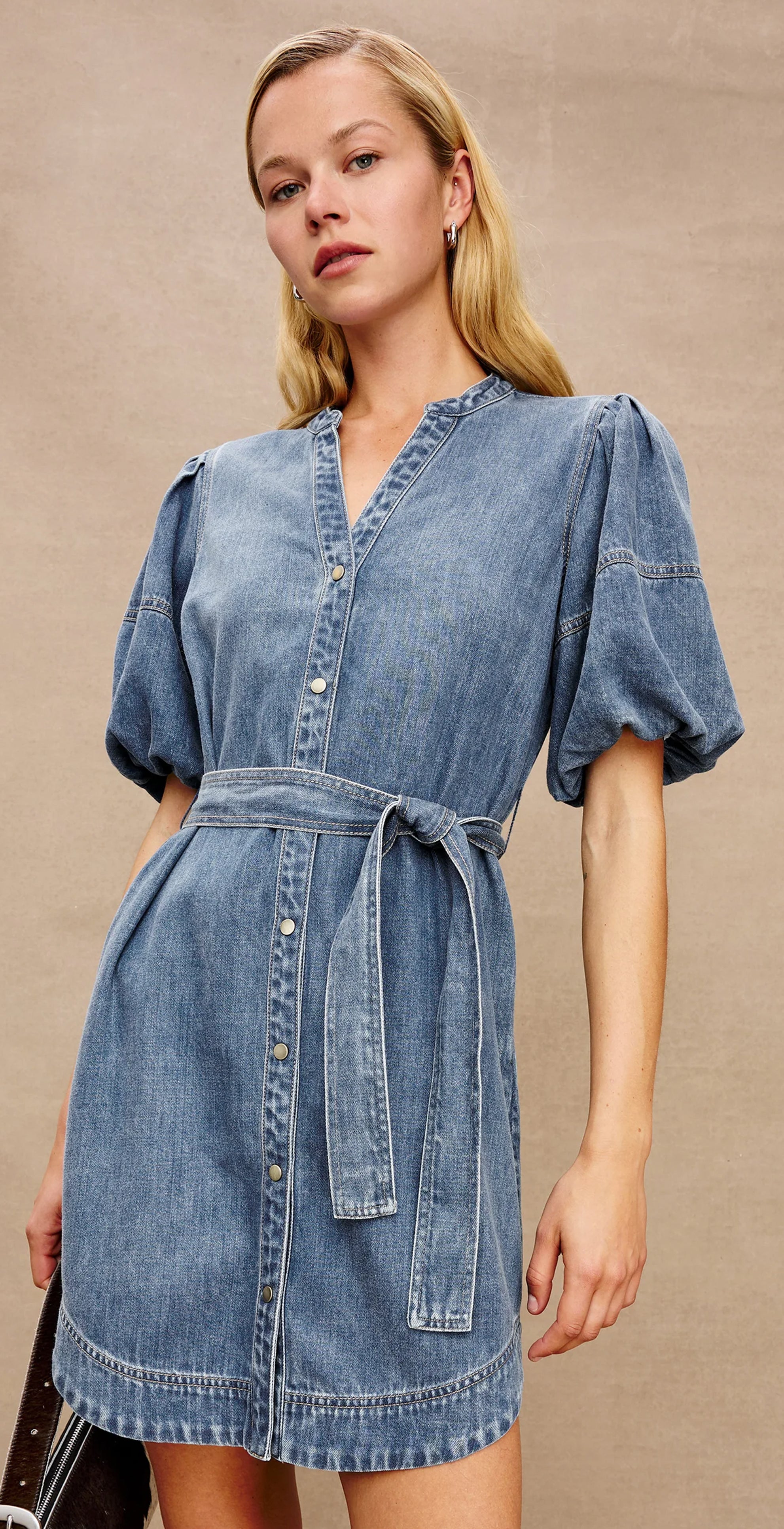 Woman wearing a denim dress against a beige background