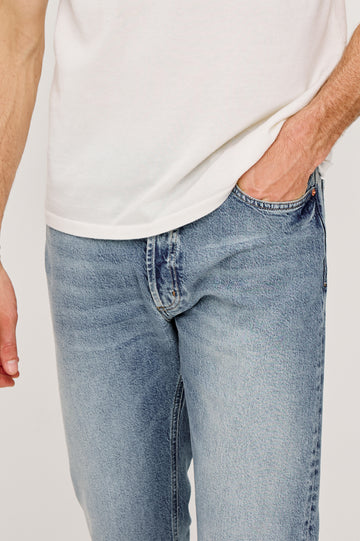 Nash is a straight leg 5-Pocket denim jean a zip fly and button closure as well as rivets in a Medium Vintage Wash. Front detail view featured on model.