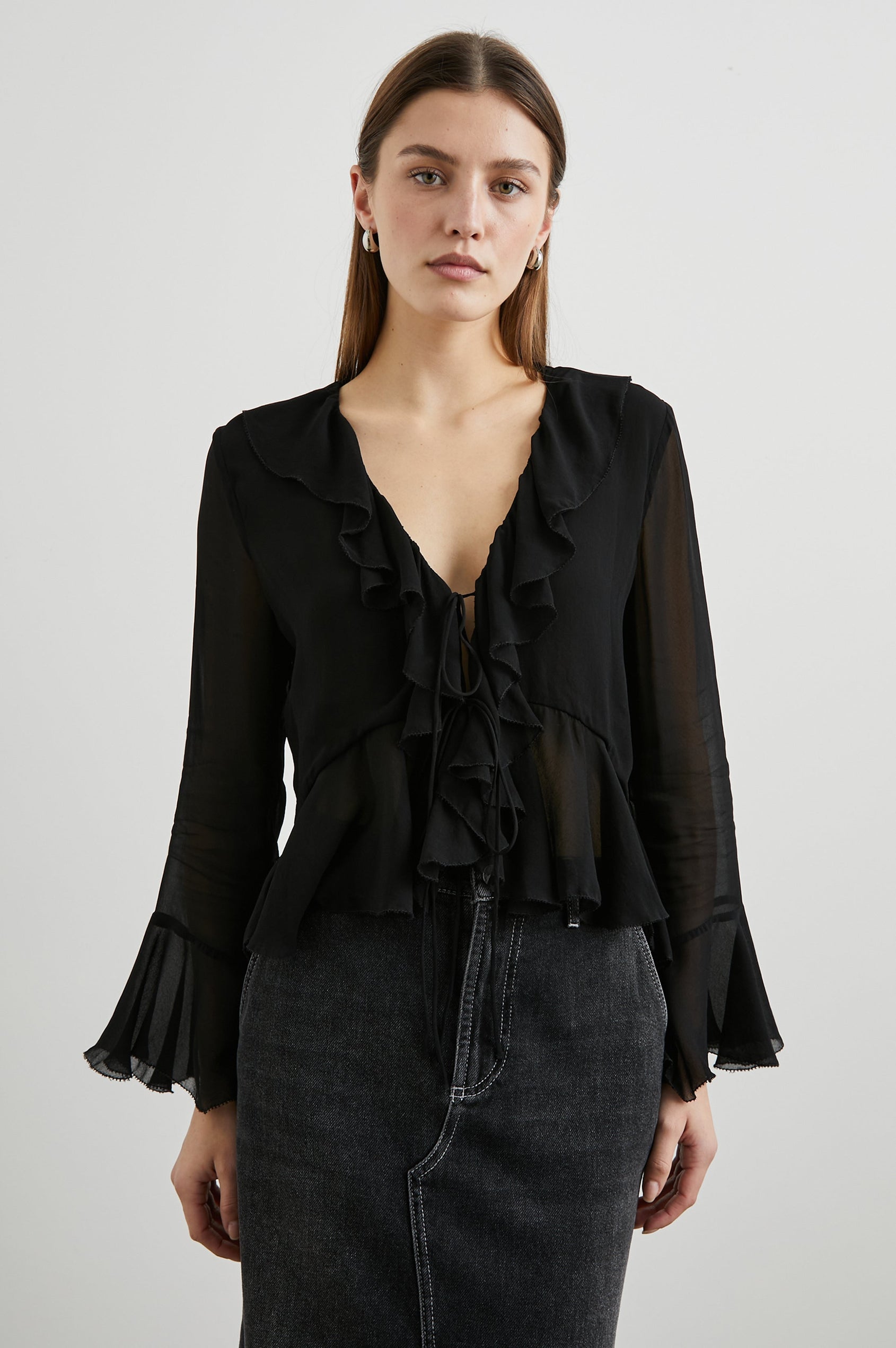 Nicoletta Long-Sleeve Semi-Sheer Top with Deep V Neck, Front Tie Closure, and Ruffled Trim in Black Colorway - Front View Featured on Model