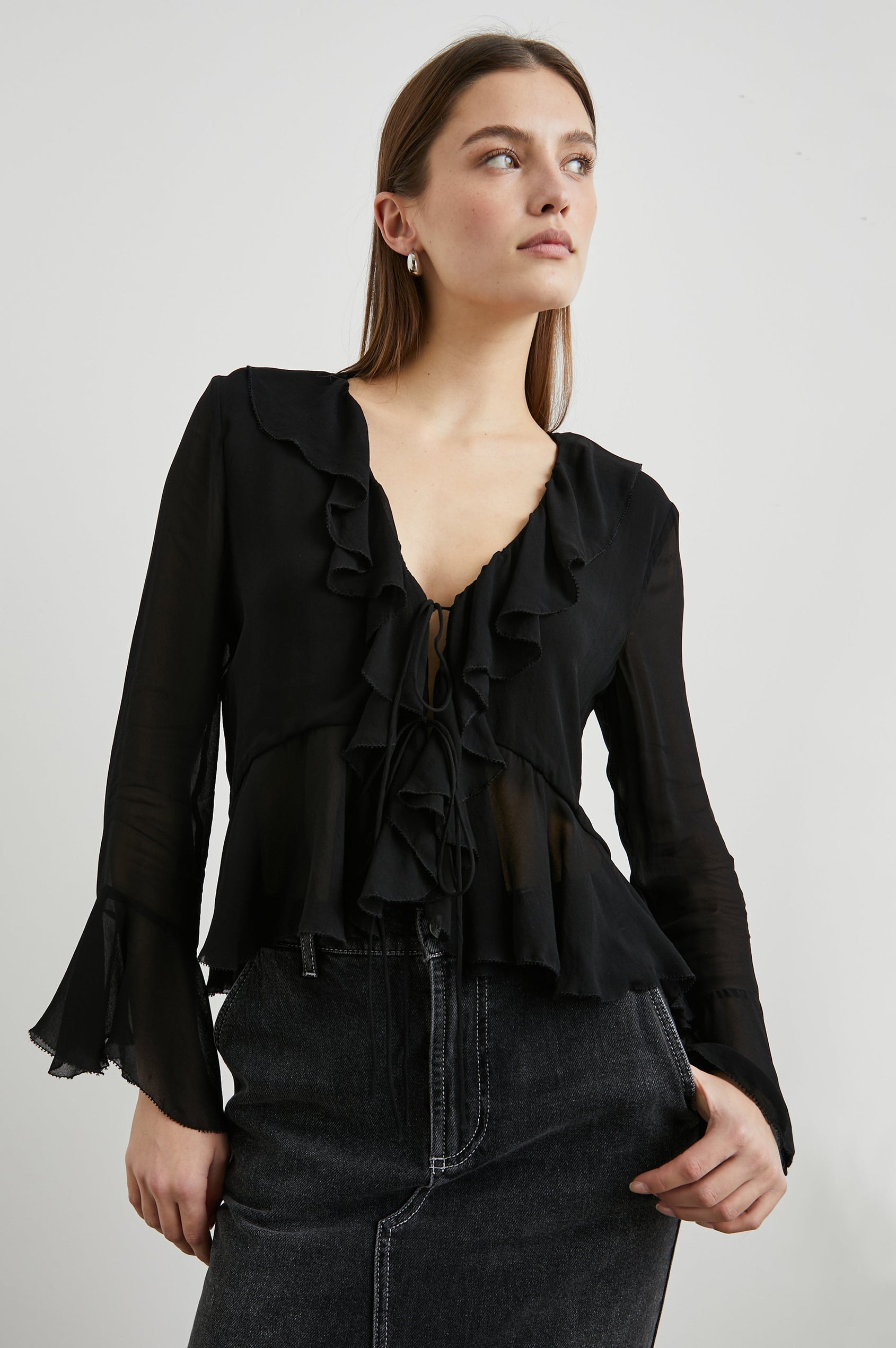 Nicoletta Long-Sleeve Semi-Sheer Top with Deep V Neck, Front Tie Closure, and Ruffled Trim in Black Colorway - Front View Featured on Model