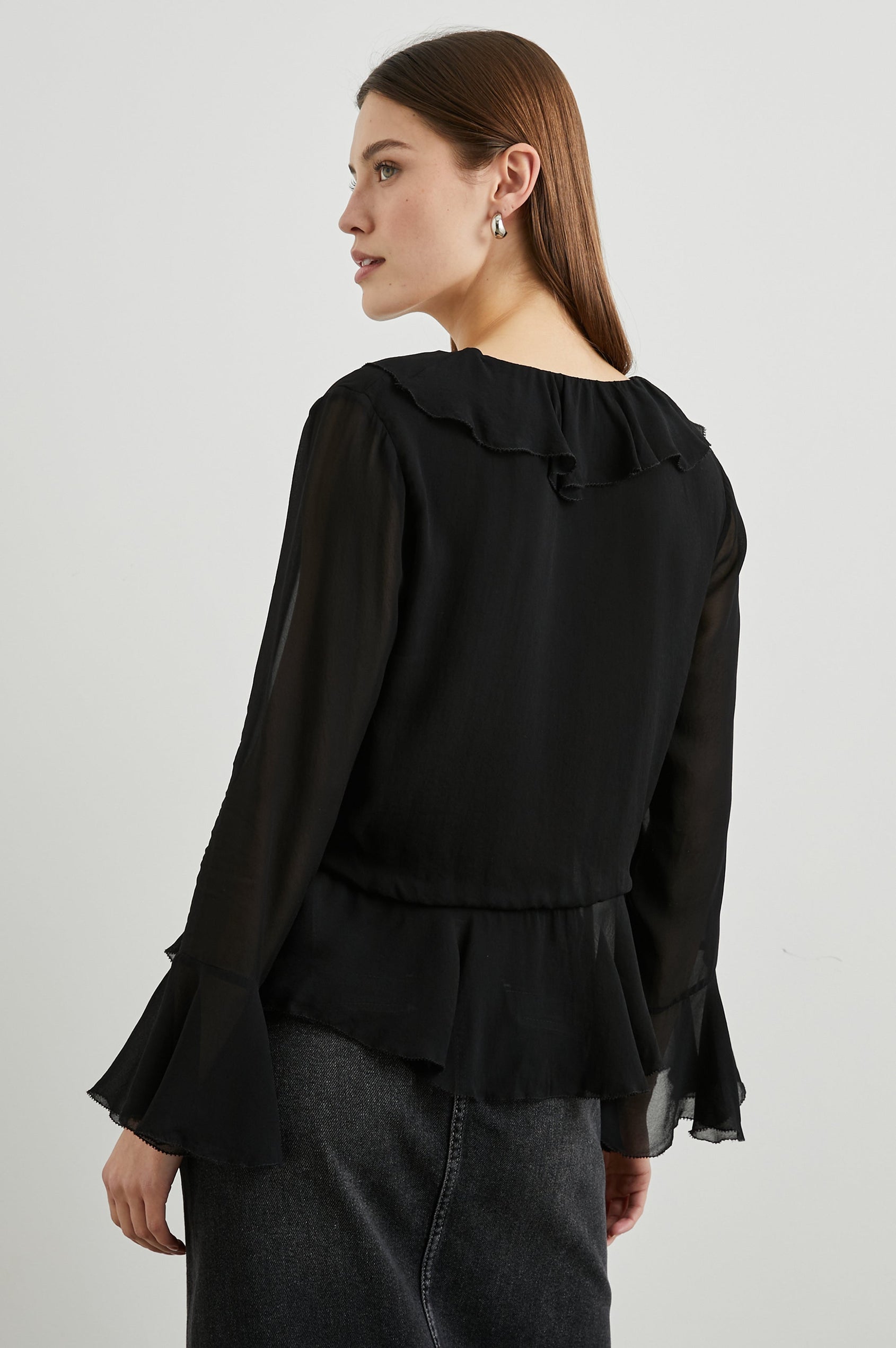 Nicoletta Long-Sleeve Semi-Sheer Top with Deep V Neck, Front Tie Closure, and Ruffled Trim in Black Colorway - Back View Featured on Model