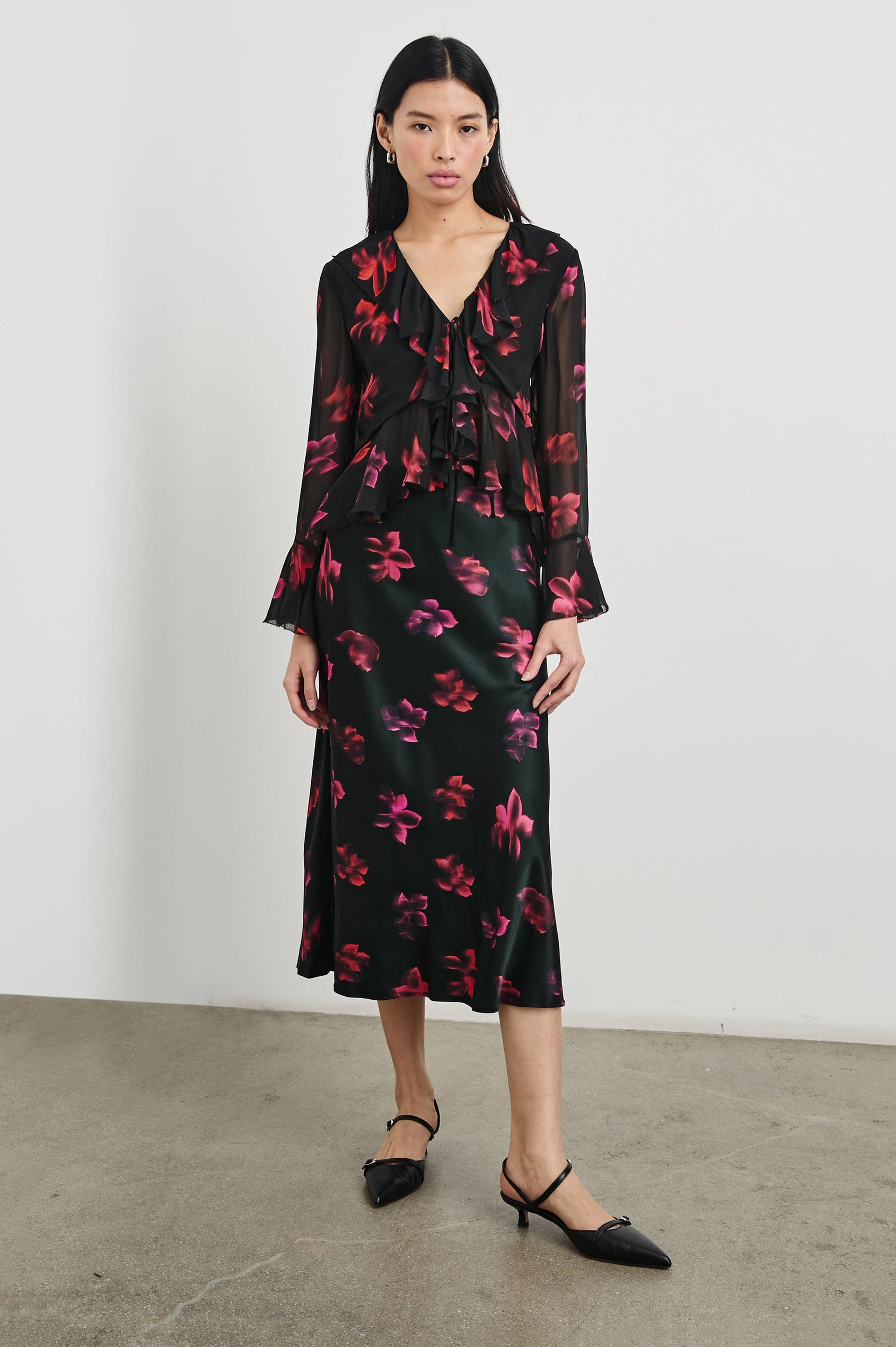 Nicoletta Long-Sleeve Semi-Sheer Top with Deep V Neck, Front Tie Closure, and Ruffled Trim in Dark Azalea Colorway, Flowers in pinks and purple on Black - Front Full Body View Featured on Model