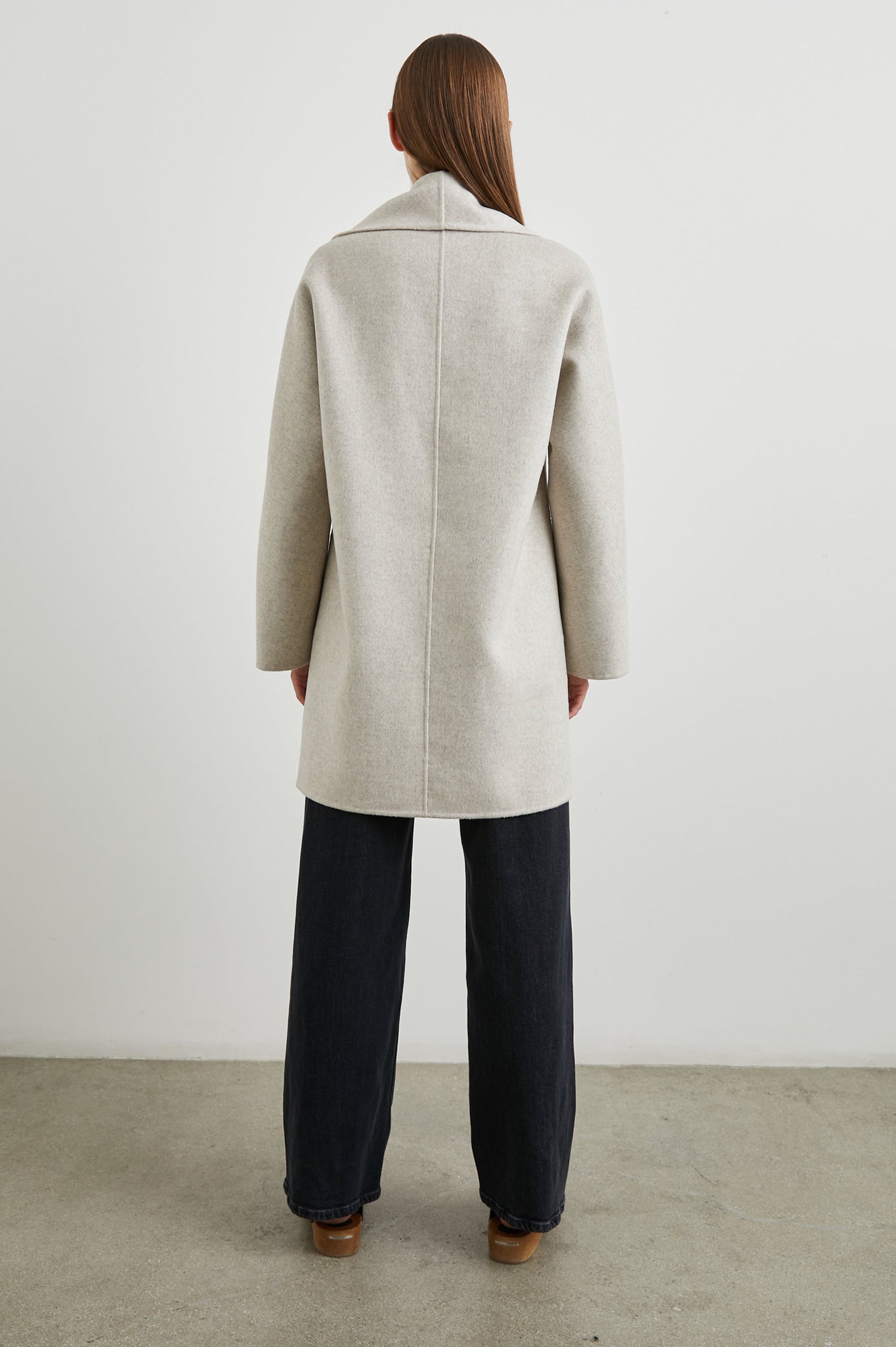 Nily Mid-Thigh Length, Double-Breasted Coat with Two Button Closure, Two Front Patch Pockets and a Shaw Collar in Oatmeal Colorway - Back Full Body View Featured on Model 