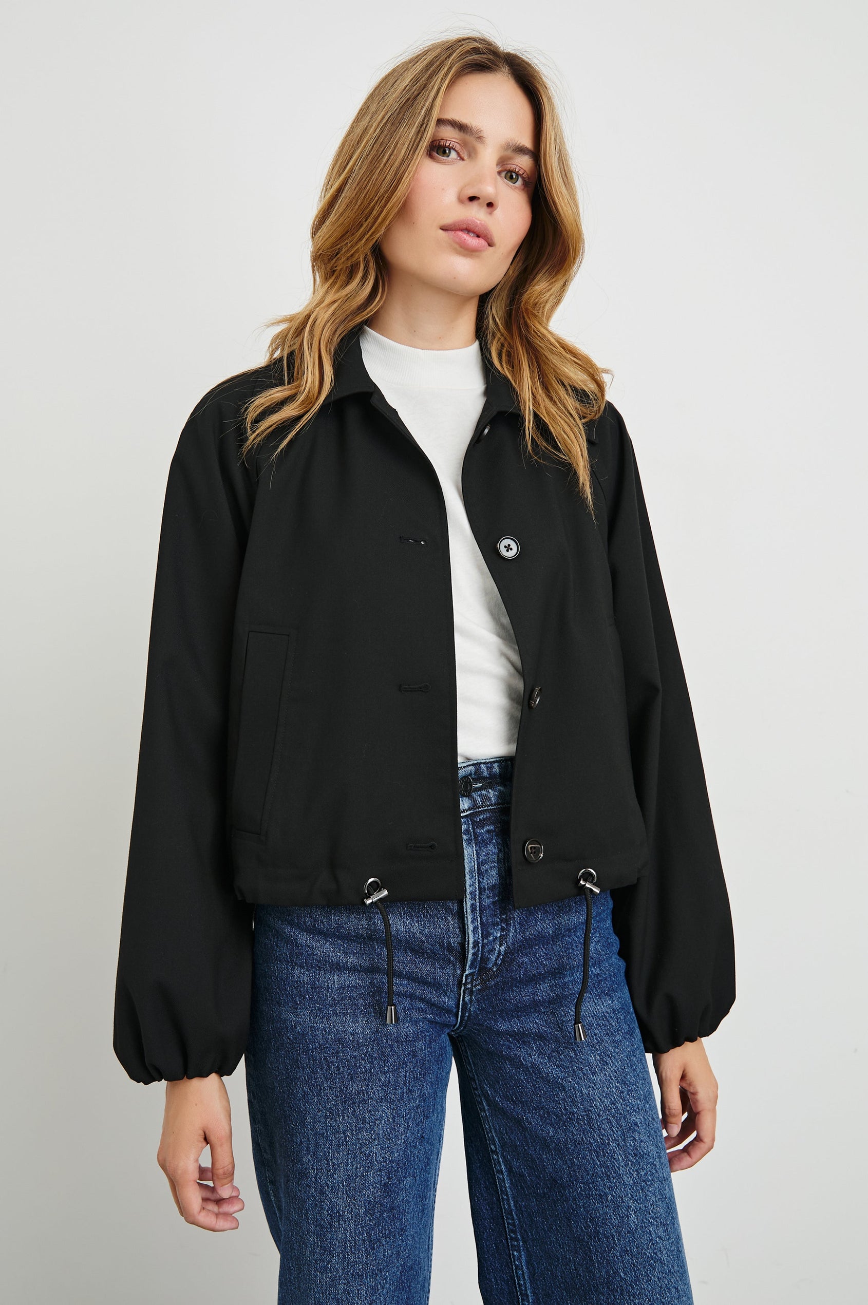 North Cropped Jacket with Button Closure, Puff Sleeves, Oversize Collar, a Toggle Hem, Two Front Pockets and a Horizontal Back Vent in Black Twill Colorway - Front View Featured on Model