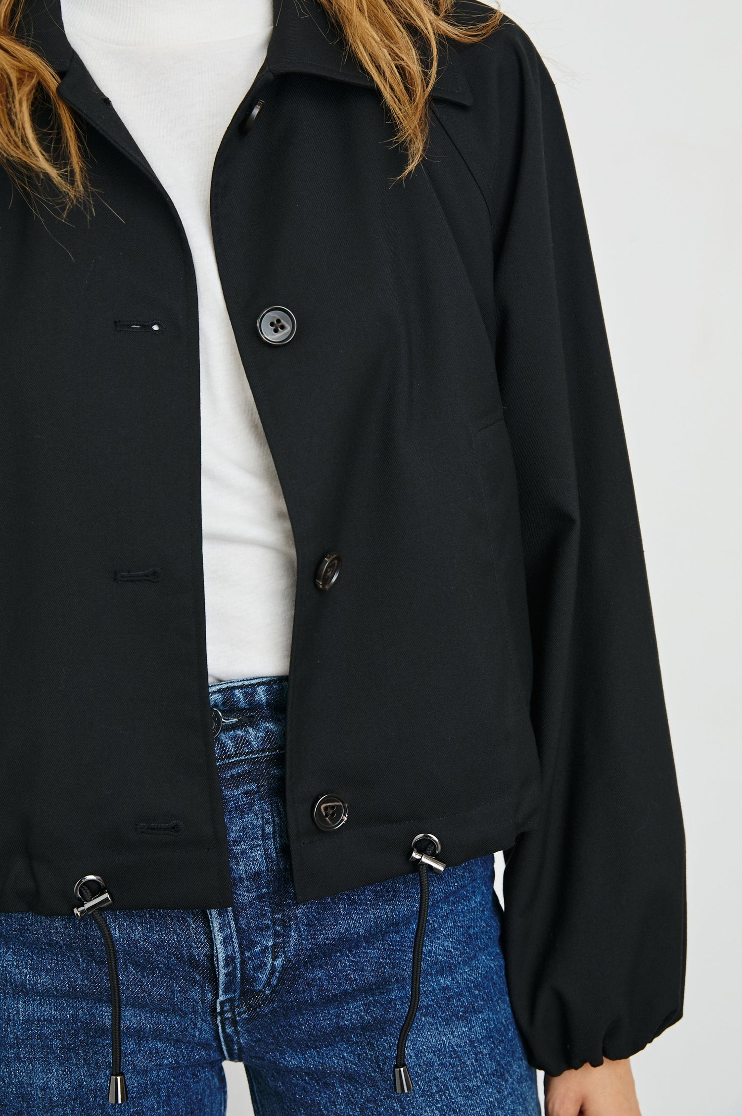 North Cropped Jacket with Button Closure, Puff Sleeves, Oversize Collar, a Toggle Hem, Two Front Pockets and a Horizontal Back Vent in Black Twill Colorway - Front View Featured on Model