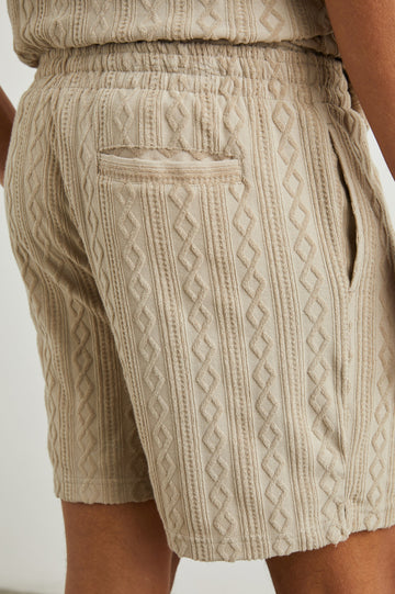 Nova Shorts with a Drawstring Waist, a Raised Jacquard Pattern, Two Front Pockets and a Back Patch Pocket in Craft Paper Colorway, a Light Brown - Back View Featured on Model