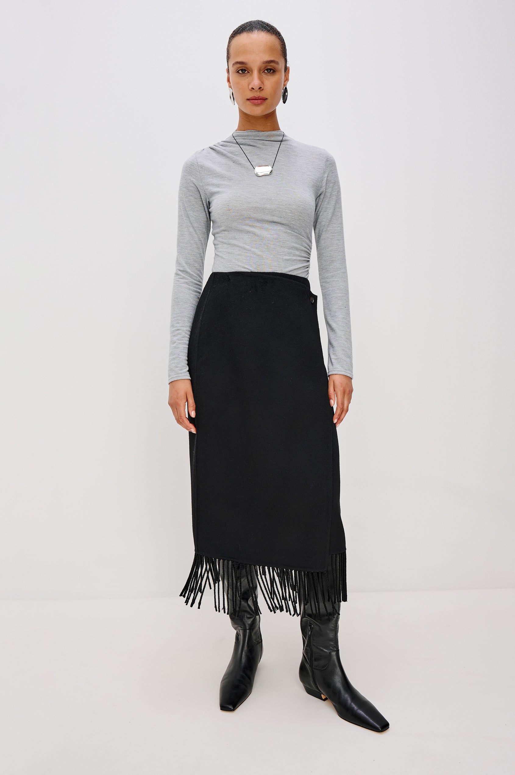 Odette Midi Skirt in Wool Blend With Wrap Design, Hidden Side Button Closure, and Fringe Hem in Black Colorway - Full Body Front View Featured on Model