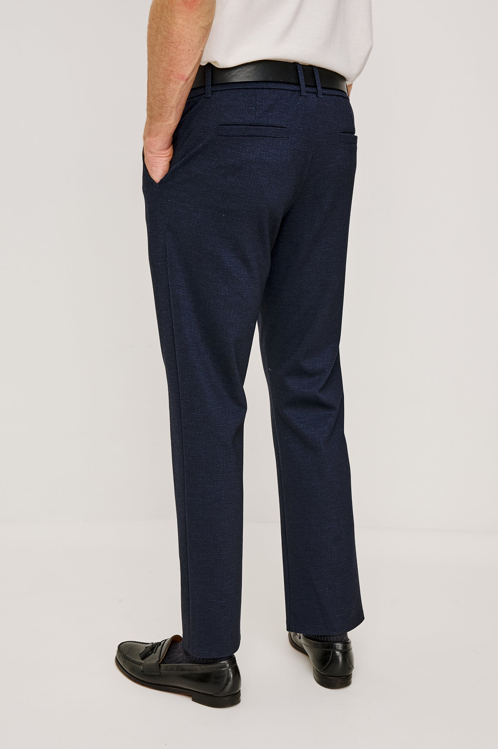 The Olivier is a trouser with a front zip fly, belt loops, side pockets, and pintuck detailing in Navy colorway. Back view featured on model.
