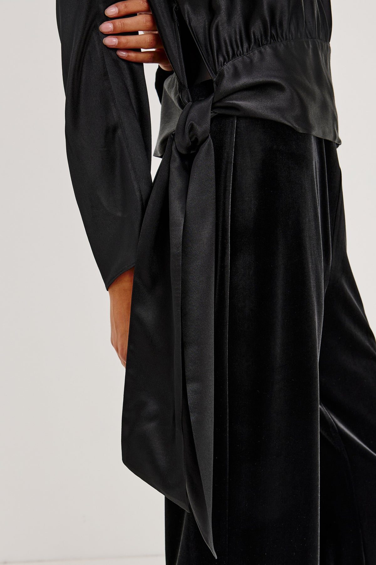 Opal Long-Sleeve Top in Luxe Satin With a Self Tie Hem in Black Colorway - Side Crop Detail View Featured on Model.