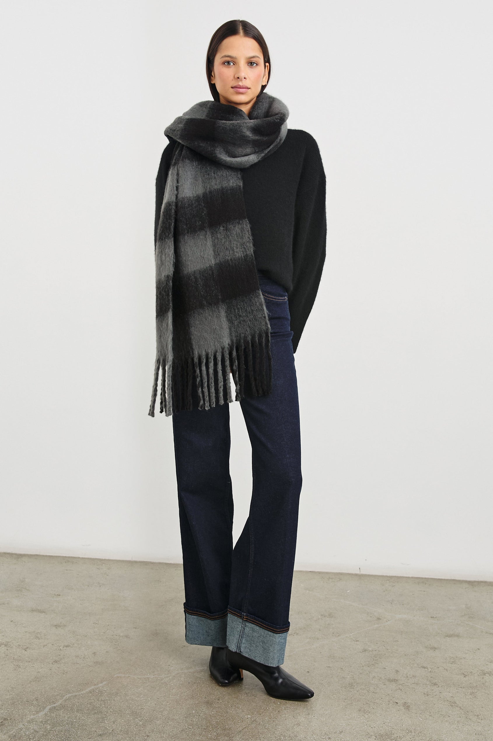 Oslo Scarf with Twisted Tassels and a Checkered Pattern in Charcoal Black Colorway - Front Full Body View Featured on Model
