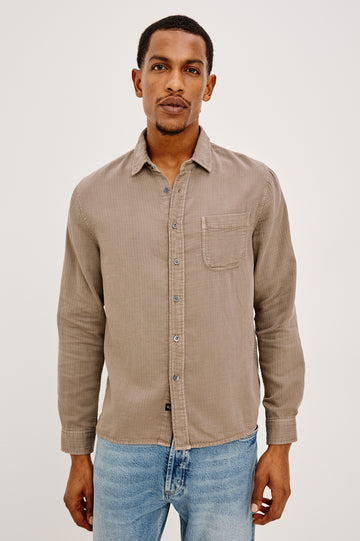 Owens is a long sleeve, collared, button front shirt lightweight cotton, long sleeve, and features a subtle pattern variation on the backside of the fabric in Desert Path colorway. Front view featured on model.