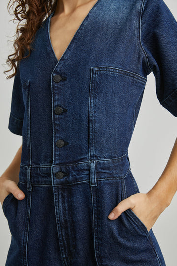 Palisades Short Sleeve Denim Jumpsuit with Wide Legs and Sleeves, Belt Loops, A Button and Zipper Closure for the Pants and Button Closure on the Bodice, a V neck, two Front Pockets and Two Back Patch Pockets in Blue Moon Colorway - Front View Featured on Model
