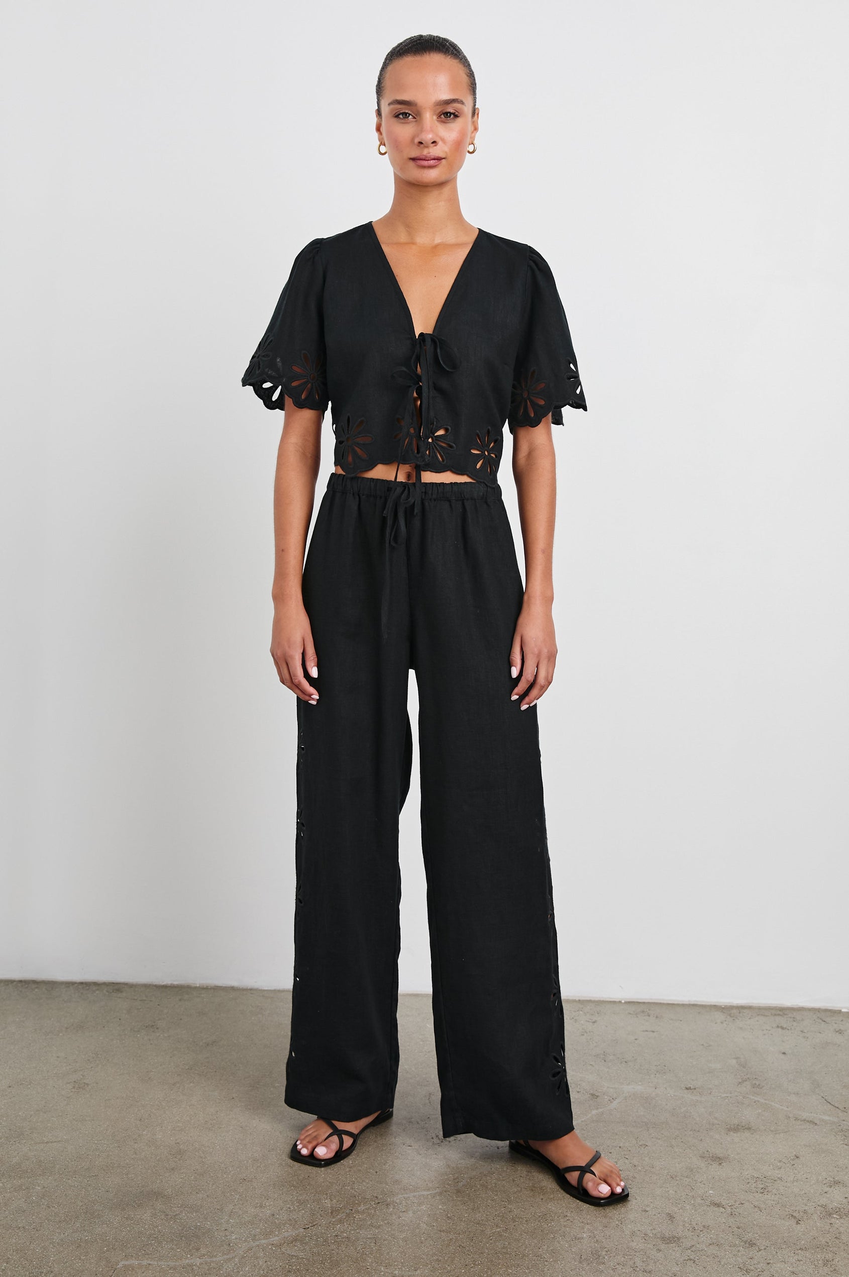 Pari Short-Sleeve Cropped Top with V Neck, Front Tie Closures, and Floral Eyelets in Black Eyelet Colorway - Front Full Body View Featured on Model 