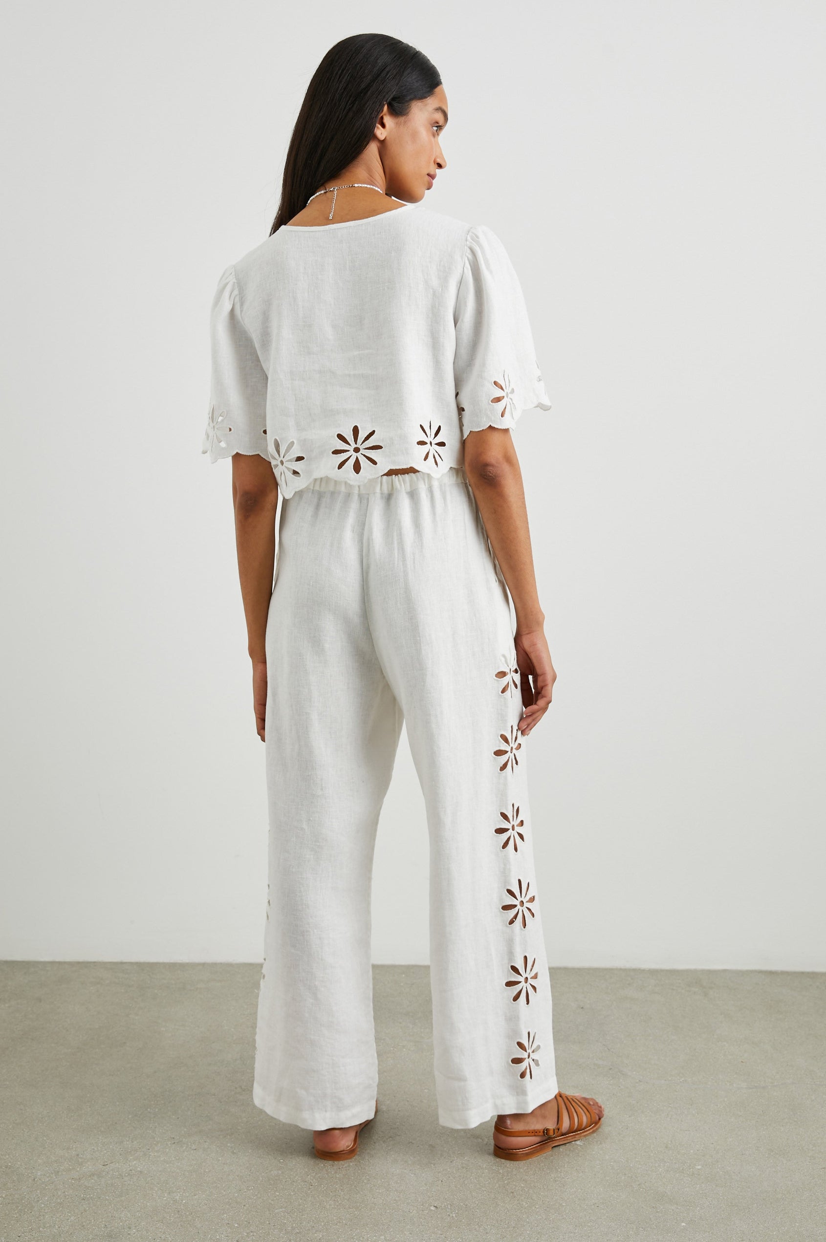 Pari Short-Sleeve Cropped Top with V Neck, Front Tie Closures, and Floral Eyelets in White Eyelet Colorway - Side View Featured on Model 