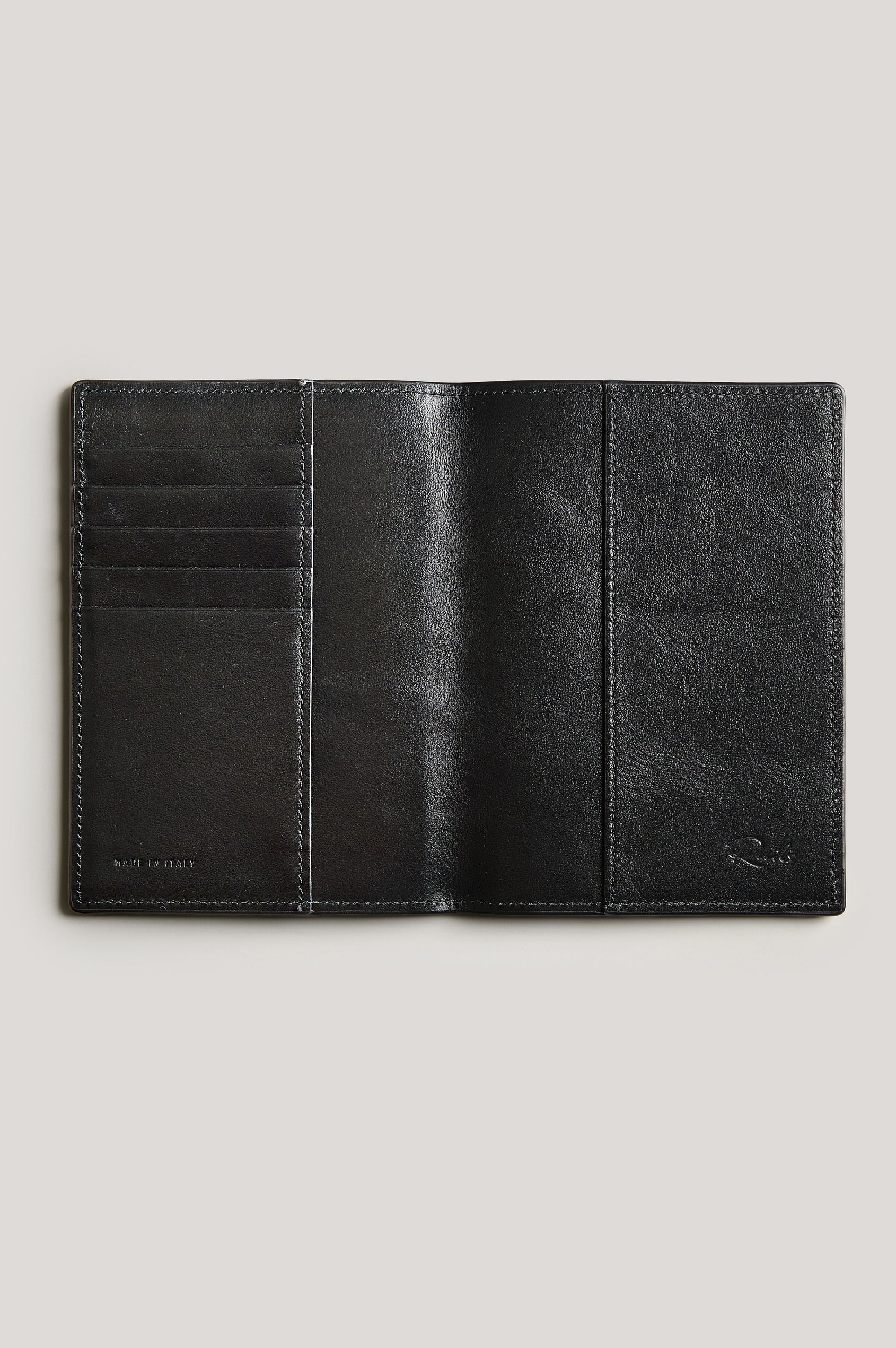 Leather passport holder opened, detailed inside view with, in Black colorway.