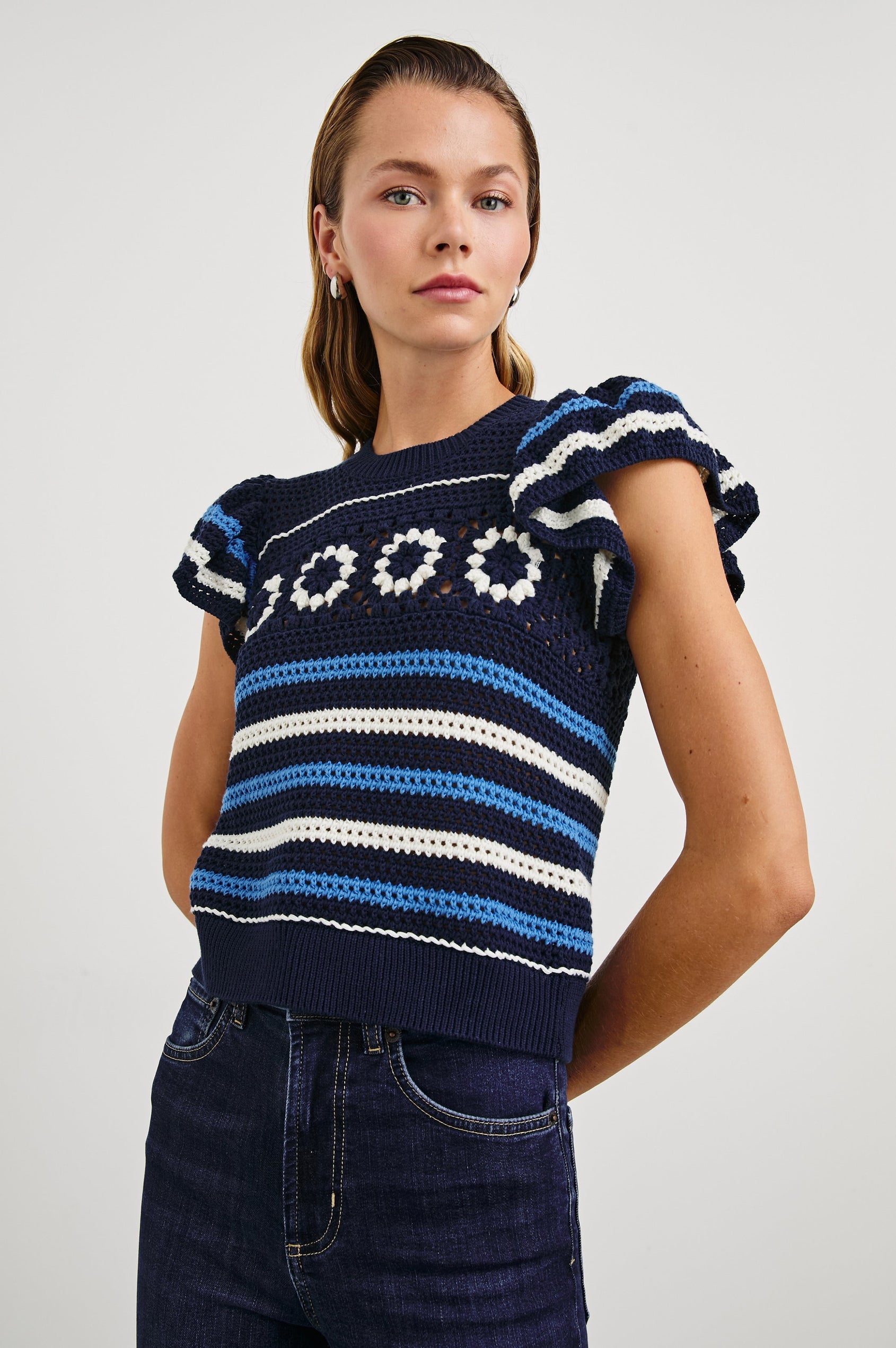 Penelope Crochet Top with Flutter Sleeves and Ribbed Hem in Navy Sky Crochet Colorway, with navy, sky blue and white Horizontal stripes and contrasting knit flowers across the chest - Front View Featured on Model