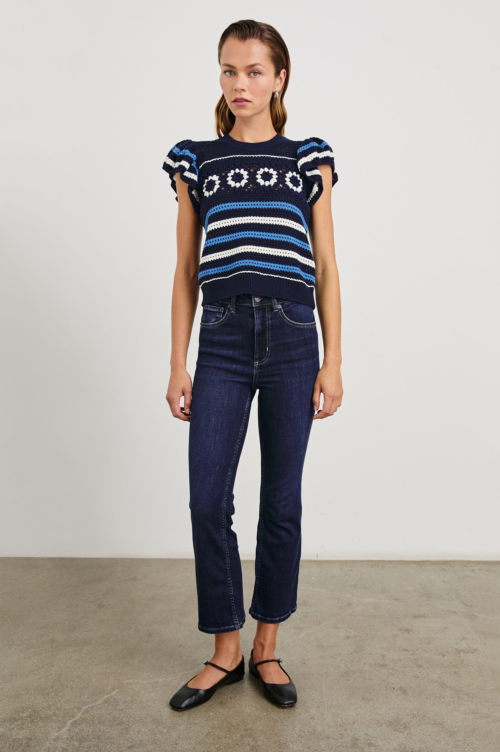 Penelope Crochet Top with Flutter Sleeves and Ribbed Hem in Navy Sky Crochet Colorway, with navy, sky blue and white Horizontal stripes and contrasting knit flowers across the chest - Front Full Body View Featured on Model