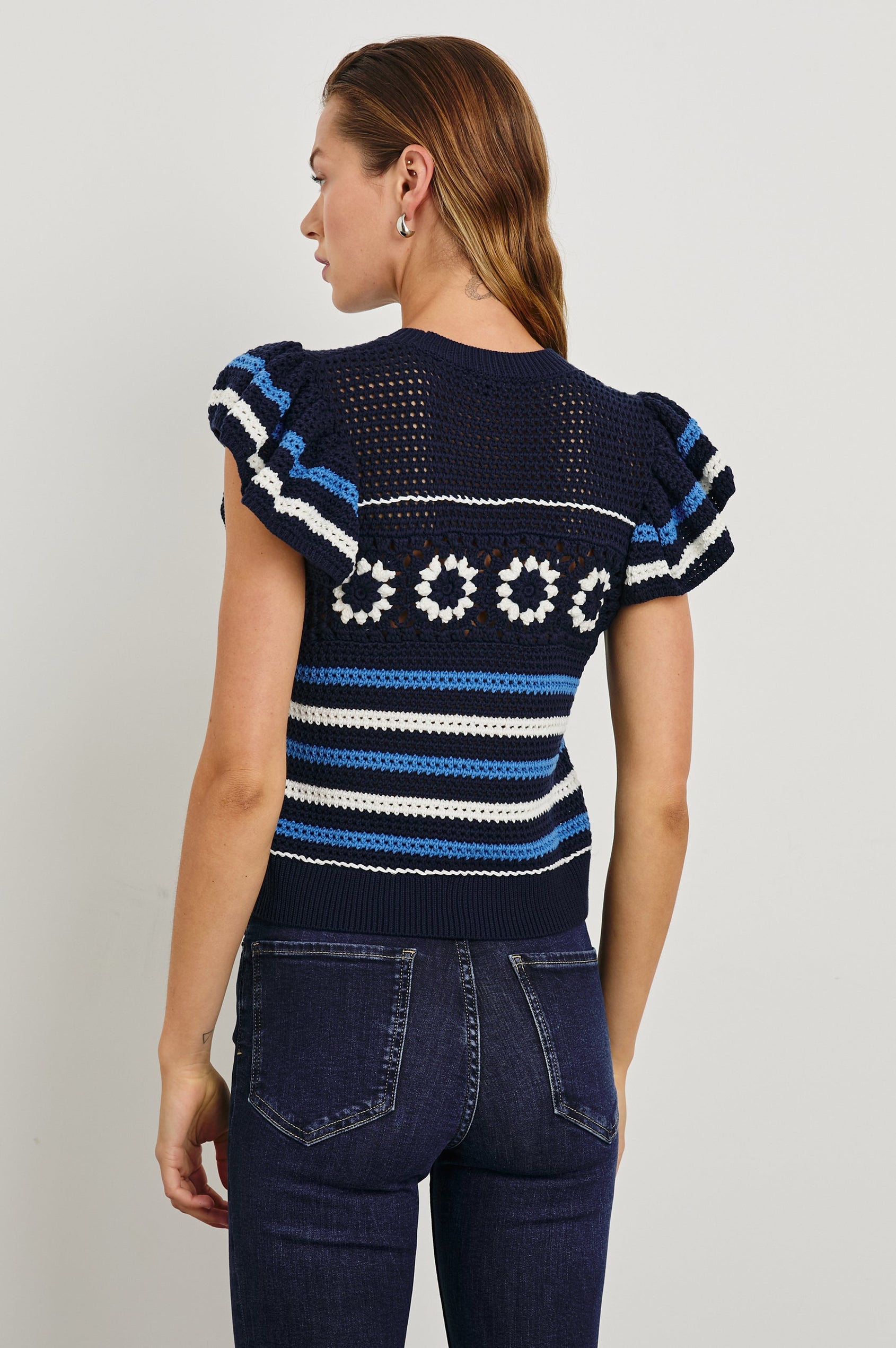 Penelope Crochet Top with Flutter Sleeves and Ribbed Hem in Navy Sky Crochet Colorway, with navy, sky blue and white Horizontal stripes and contrasting knit flowers across the chest - Back View Featured on Model
