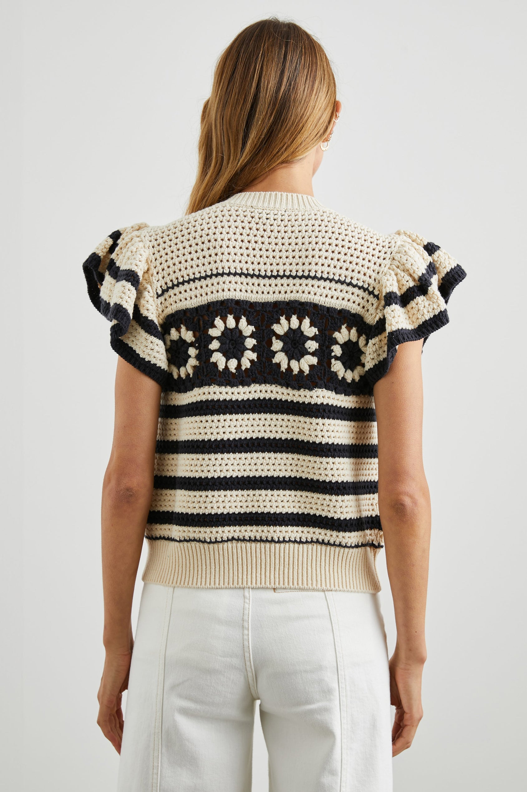 Penelope Crochet Top with Flutter Sleeves and Ribbed Hem in Oat Navy Crochet Colorway, Horizontal Stripes with contrasting knit flowers across the chest - Back View Featured on Model
