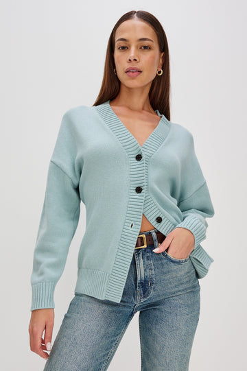 Longline cardigan in a cotton-wool blend in Stone Blue Colorway. The design features drop shoulders and a front cutaway detail, creating a soft, relaxed, and flattering silhouette. Front View on Model.