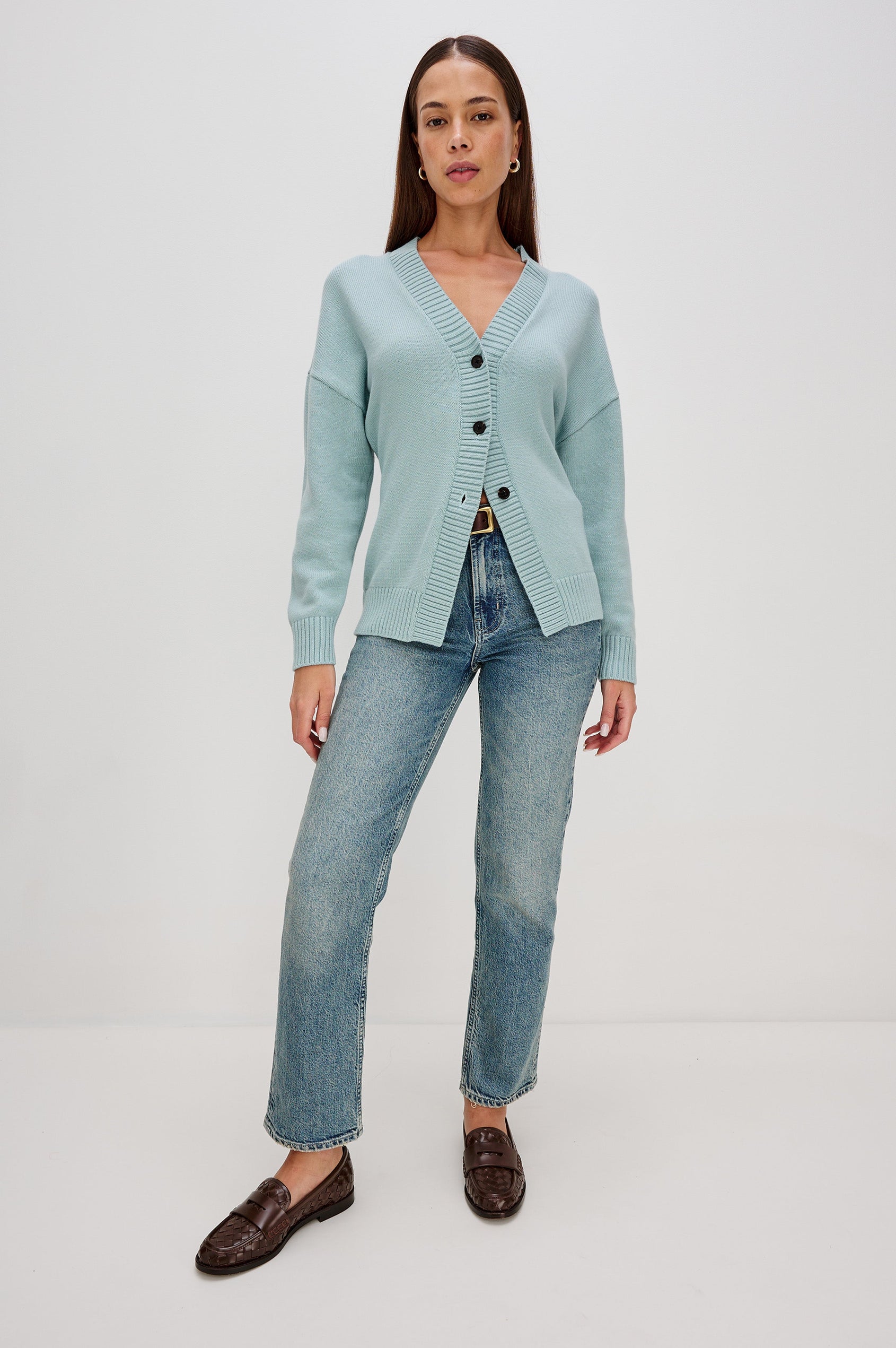 Longline cardigan in a cotton-wool blend in Stone Blue Colorway. The design features drop shoulders and a front cutaway detail, creating a soft, relaxed, and flattering silhouette. Full Body Front View on Model.