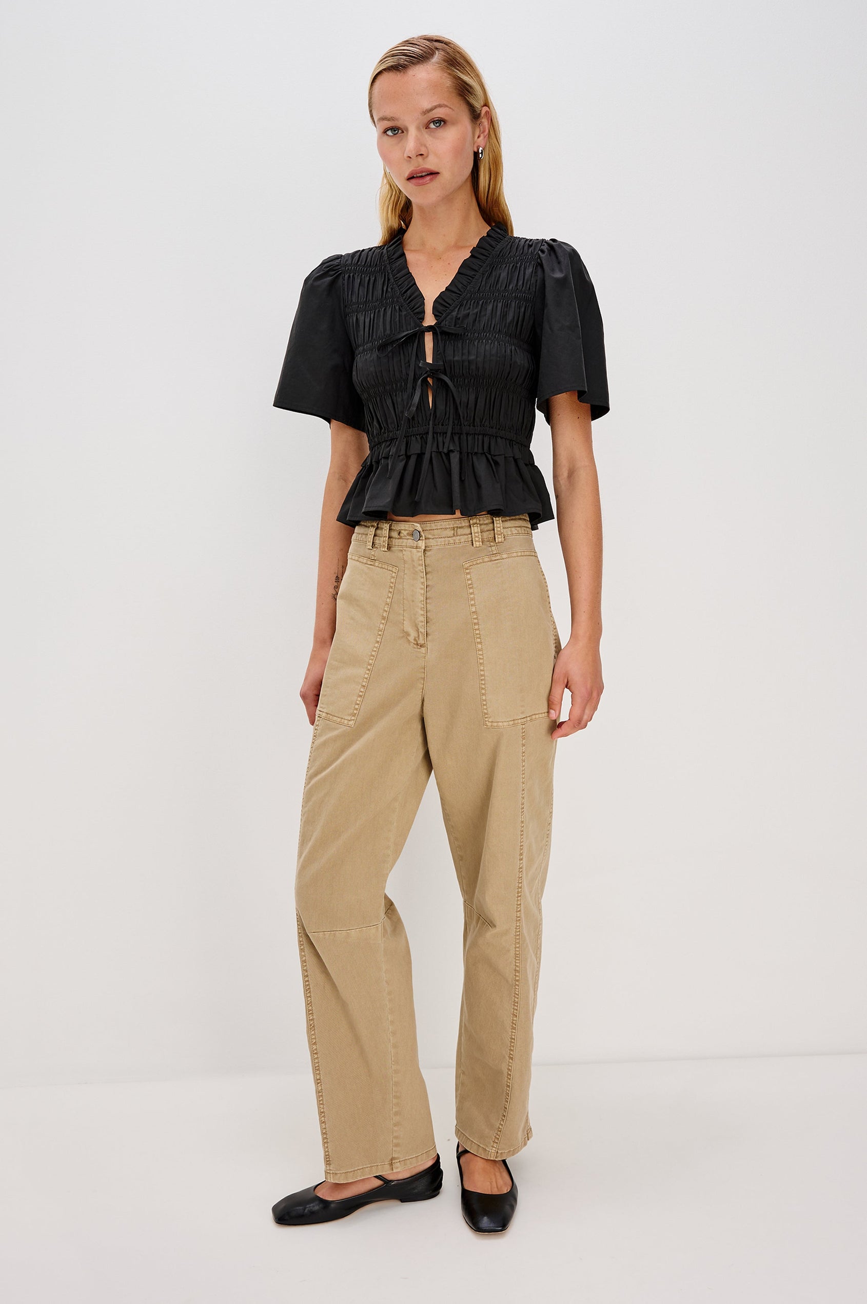 Portia V-Neck Tie Front Top with Short Puff Sleeves and a Ruffled Peplum Hem in Black Colorway. Front View Shown on Model.