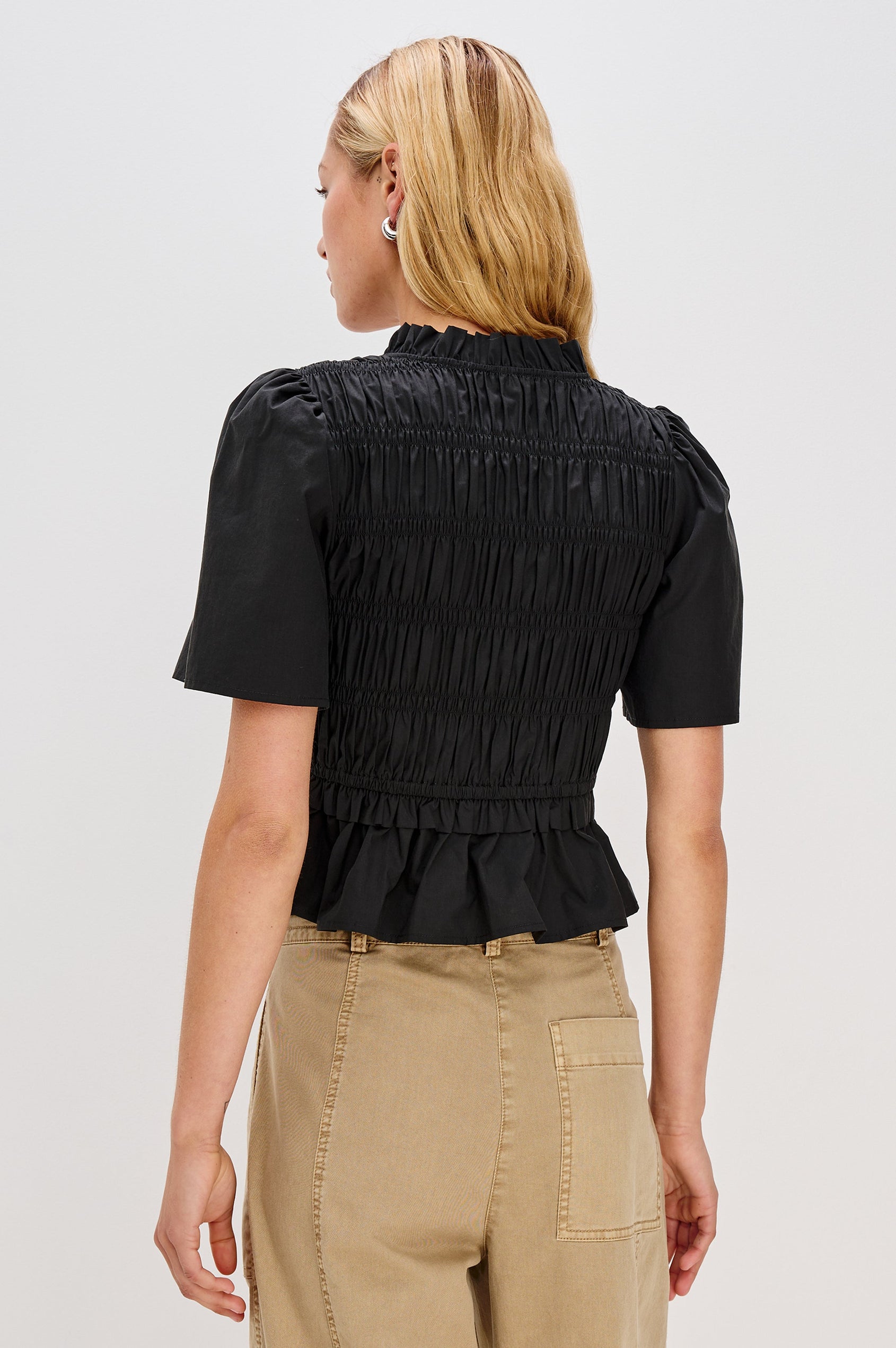 Portia V-Neck Tie Front Top with Short Puff Sleeves and a Ruffled Peplum Hem in Black Colorway. Back View Shown on Model.