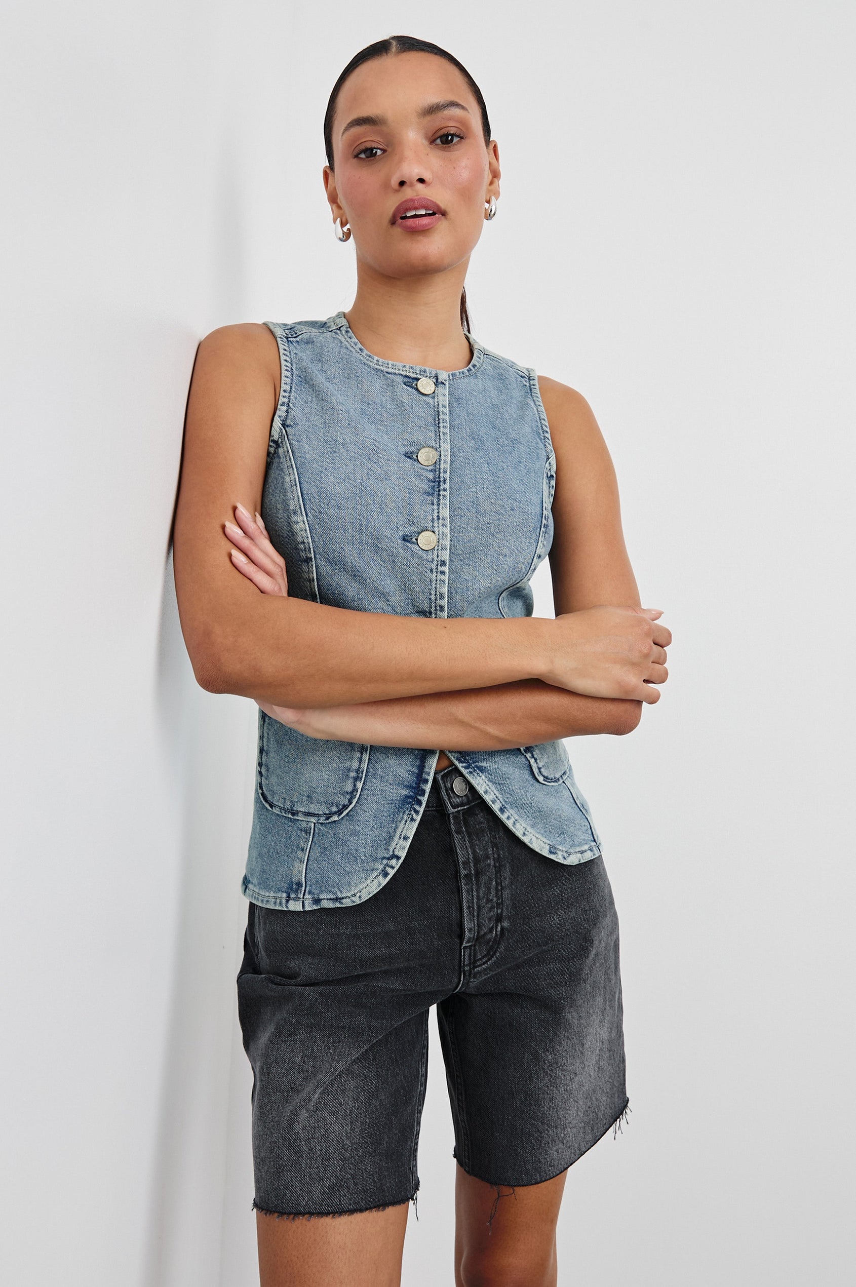 Portola Sleeveless Denim Vest with Exposed Button Front Closure, Crew Neck, Front Patch Pockets and a Scalloped Split Hem in Blue Eyed Girl Colorway. Front View Shown on Model.