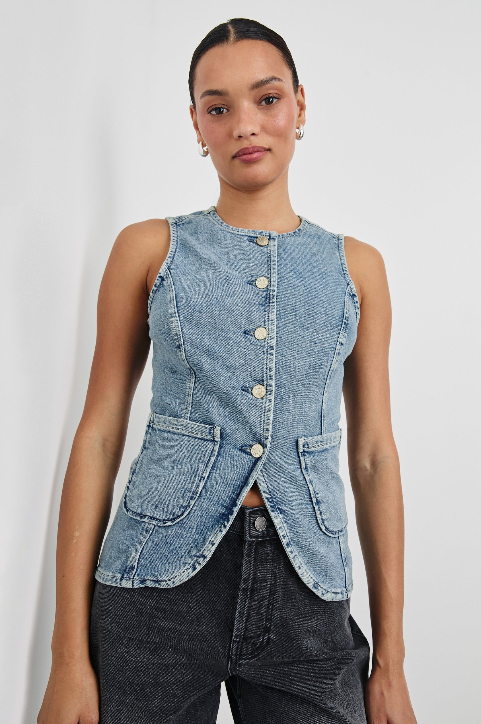 Portola Sleeveless Denim Vest with Exposed Button Front Closure, Crew Neck, Front Patch Pockets and a Scalloped Split Hem in Blue Eyed Girl Colorway. Front Detailed View Shown on Model.