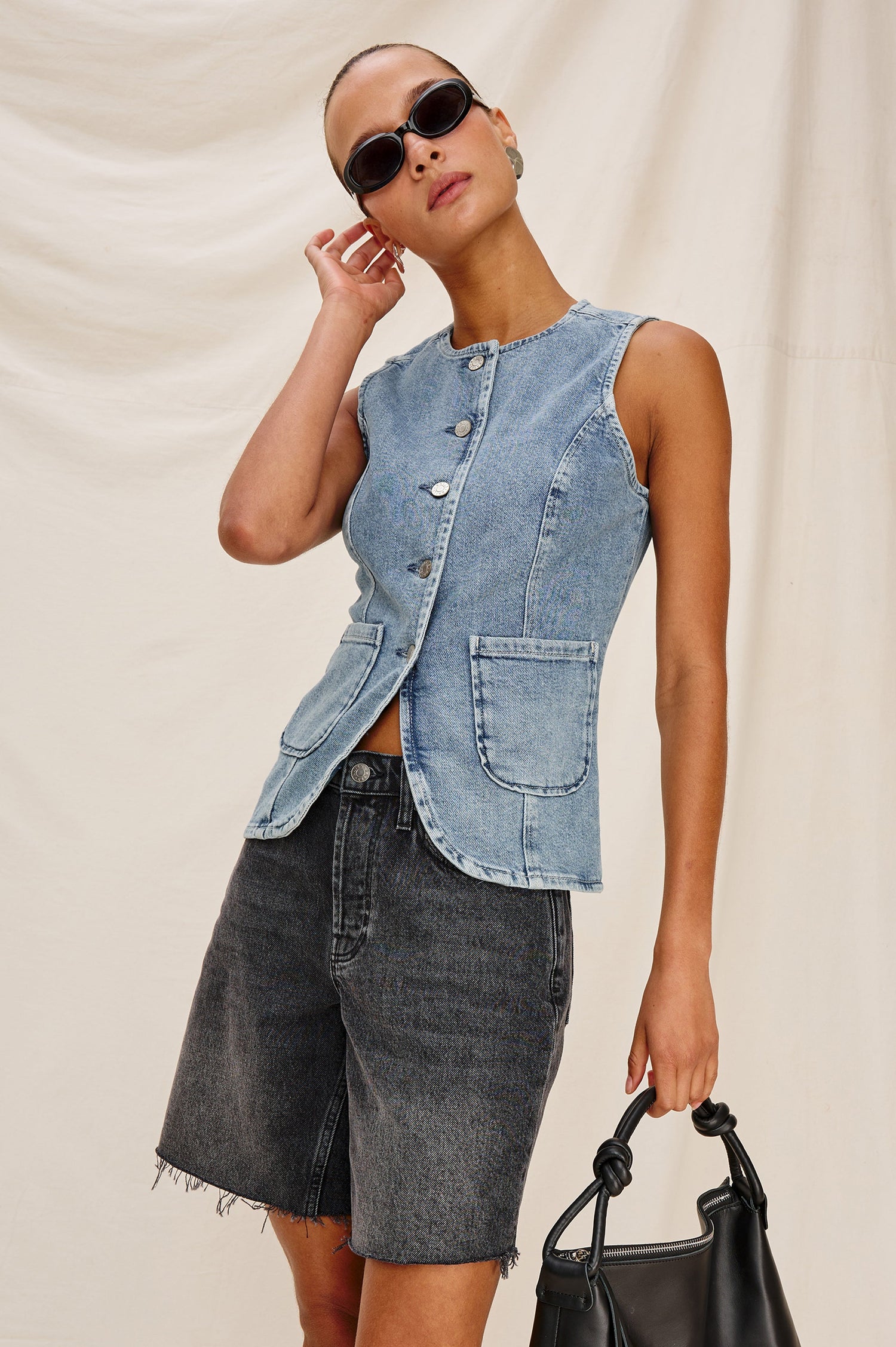 Portola Sleeveless Denim Vest with Exposed Button Front Closure, Crew Neck, Front Patch Pockets and a Scalloped Split Hem in Blue Eyed Girl Colorway. Full Body Front View Shown on Model.