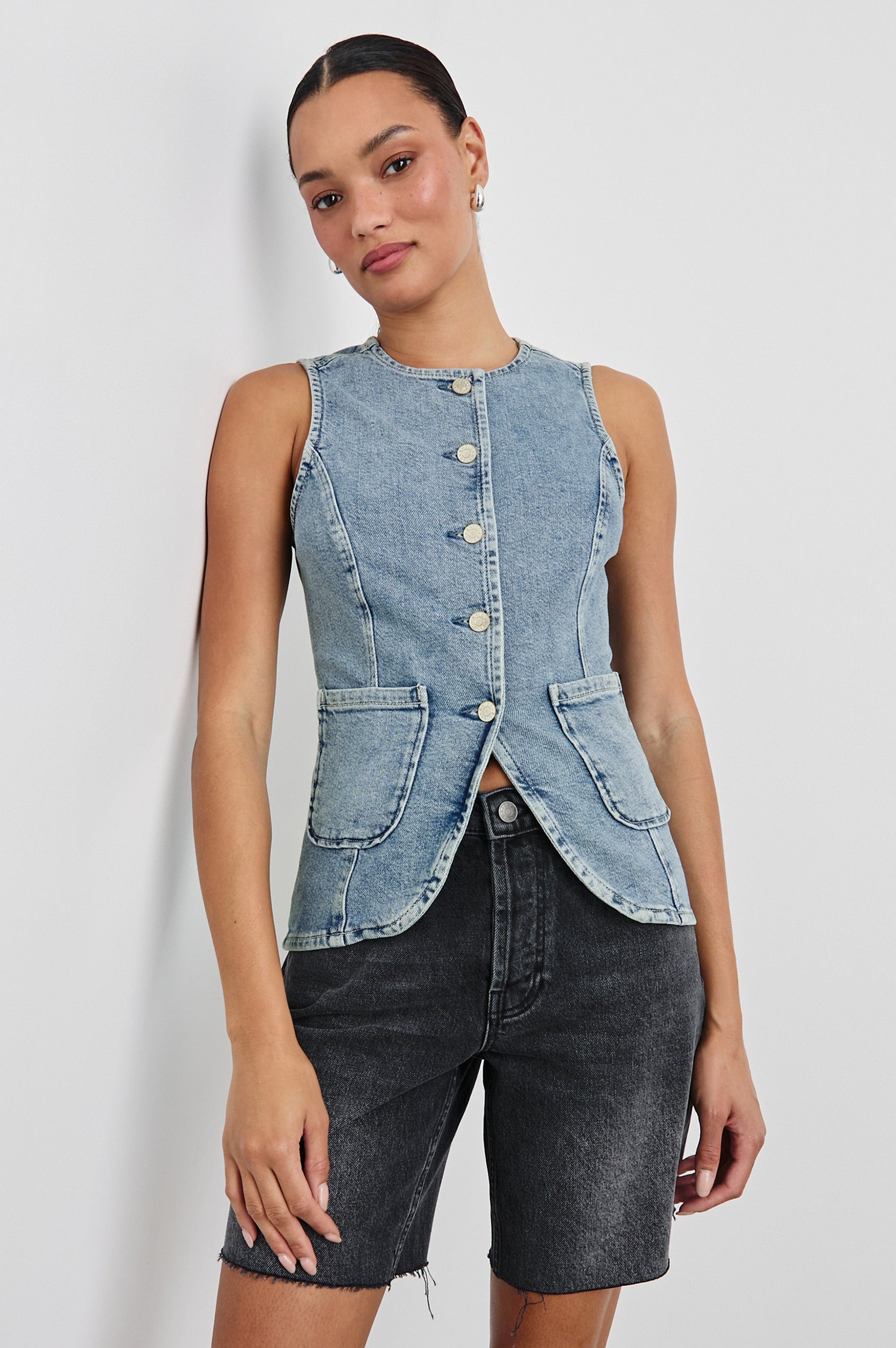 Portola Sleeveless Denim Vest with Exposed Button Front Closure, Crew Neck, Front Patch Pockets and a Scalloped Split Hem in Blue Eyed Girl Colorway. Front View Shown on Model.