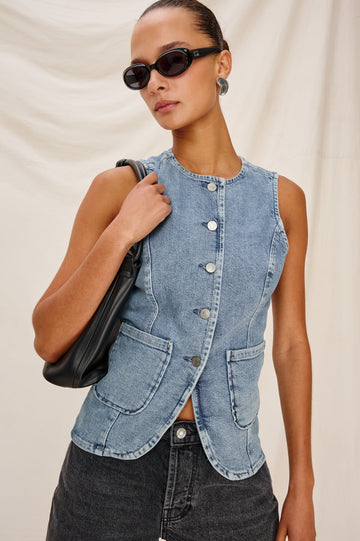 Portola Sleeveless Denim Vest with Exposed Button Front Closure, Crew Neck, Front Patch Pockets and a Scalloped Split Hem in Blue Eyed Girl Colorway. Full Body Front View Shown on Model.