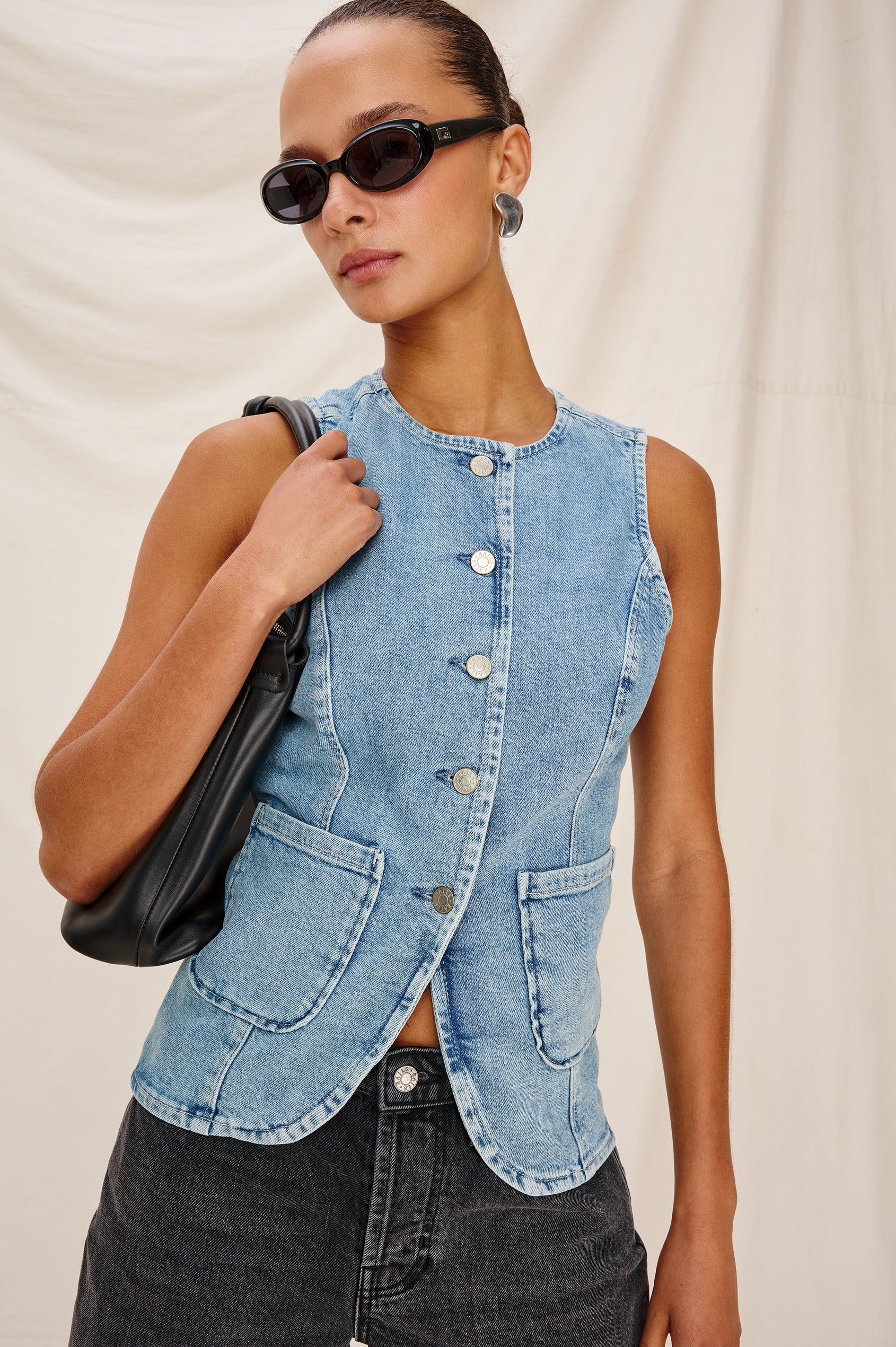 Portola Sleeveless Denim Vest with Exposed Button Front Closure, Crew Neck, Front Patch Pockets and a Scalloped Split Hem in Blue Eyed Girl Colorway. Full Body Front View Shown on Model.