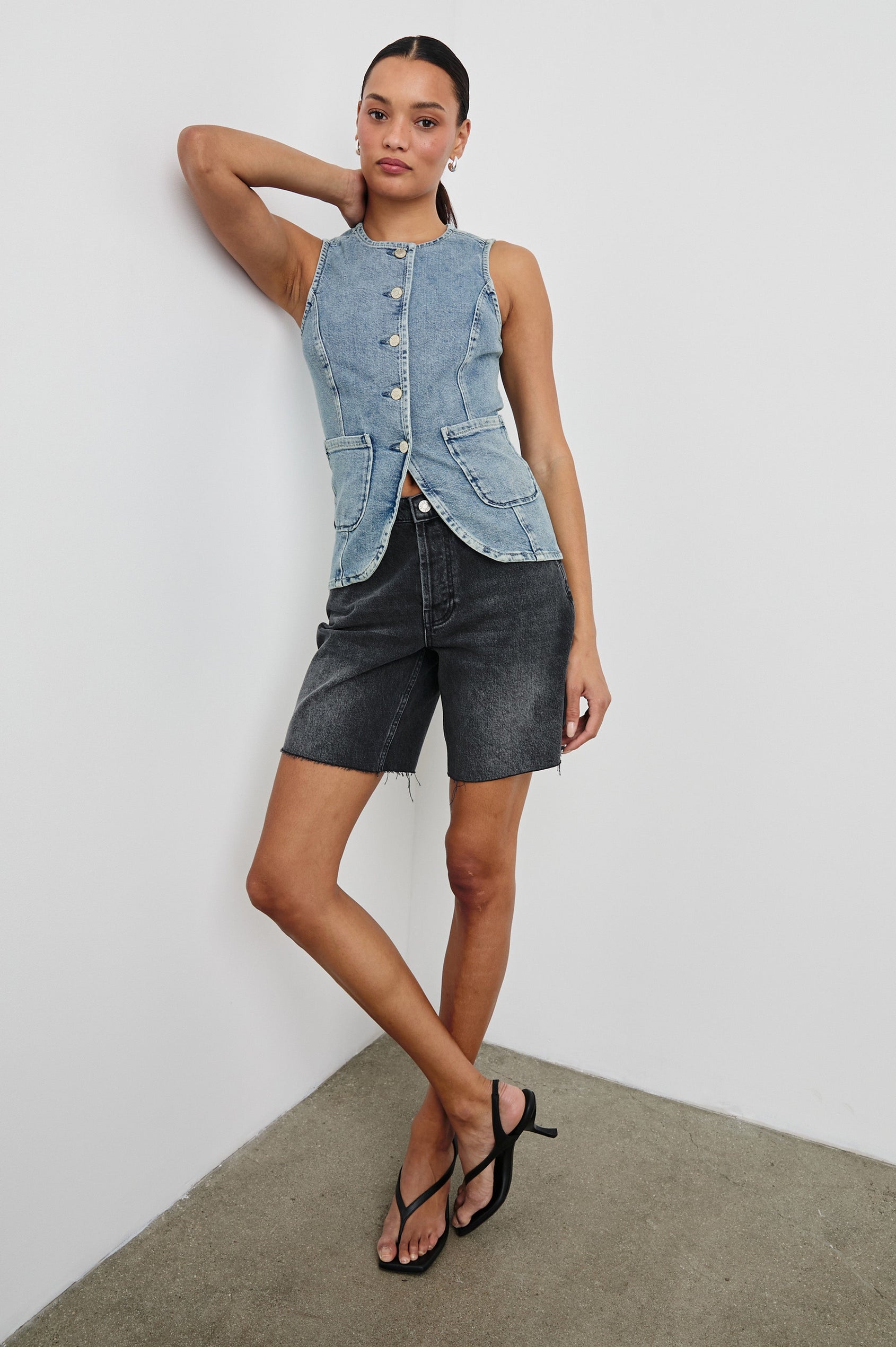 Portola Sleeveless Denim Vest with Exposed Button Front Closure, Crew Neck, Front Patch Pockets and a Scalloped Split Hem in Blue Eyed Girl Colorway. Full Body Front View Shown on Model.
