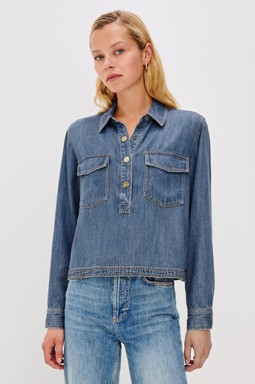 Ports is a soft, lightweight denim shirt with a cropped fit. The shirt features a half placket with snap-front closures, short sleeves, and two chest pockets in Antique Blue Colorway - Front View Featured on Model