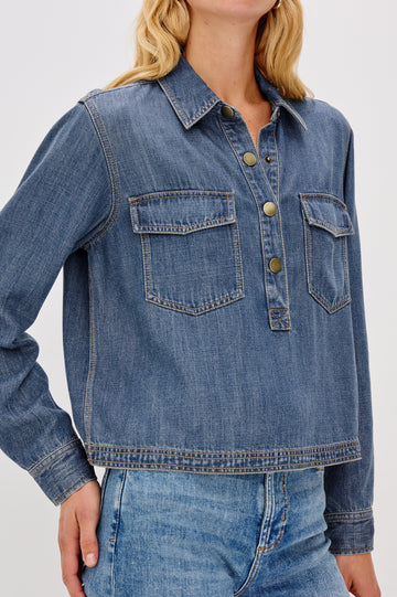 Ports is a soft, lightweight denim shirt with a cropped fit. The shirt features a half placket with snap-front closures, short sleeves, and two chest pockets in Antique Blue Colorway - Close up of Details on model