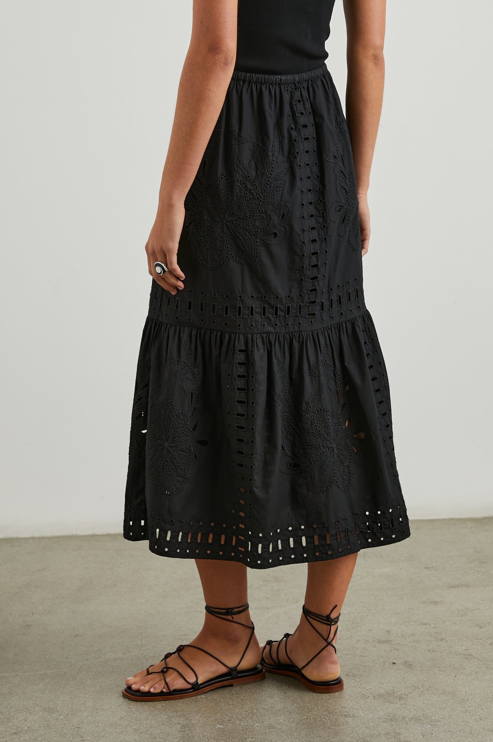 Prina Tiered Midi Skirt with a Drawstring Waist and Floral and Geometric Eyelet Details in Black Colorway - Back View Featured on Model