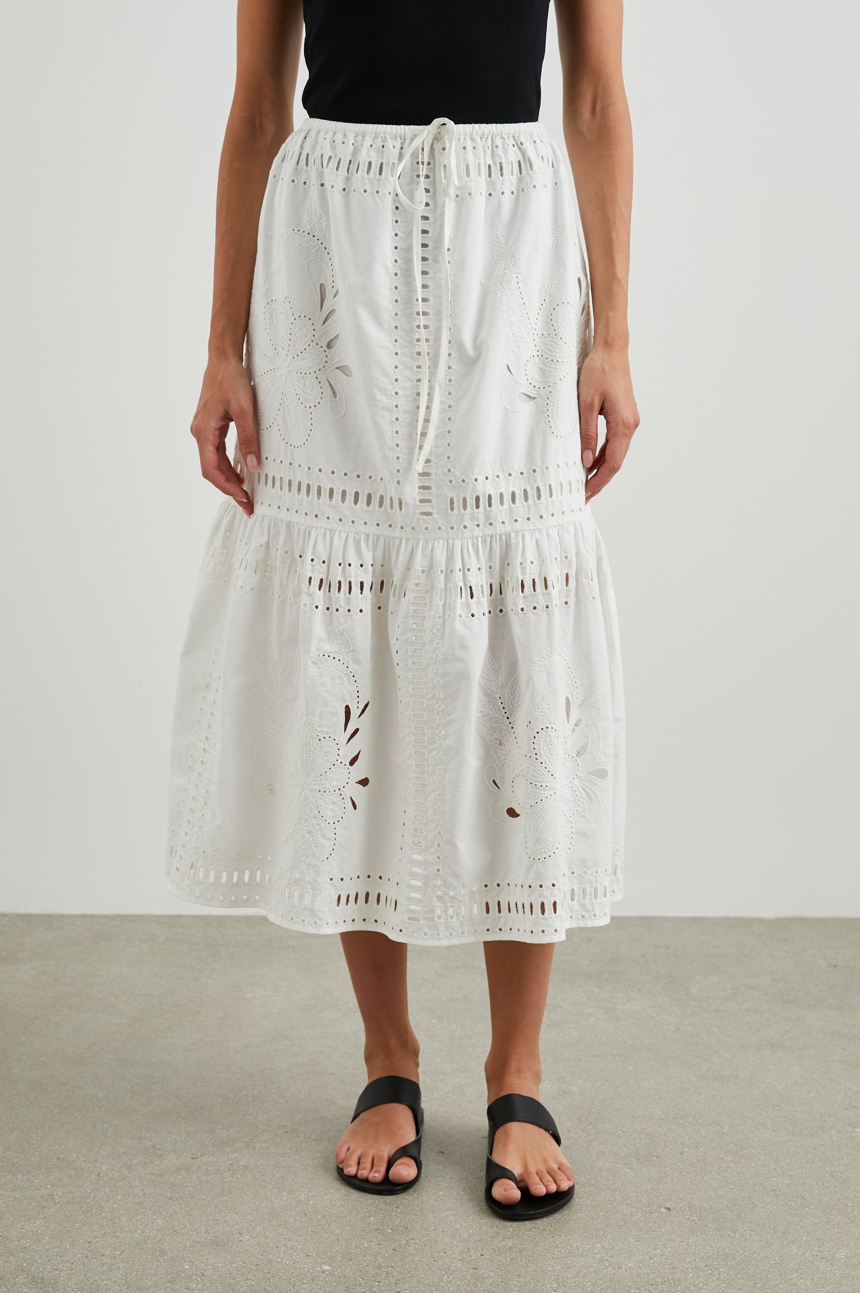 Prina Tiered Midi Skirt with a Drawstring Waist and Floral and Geometric Eyelet Details in White Colorway - Front View Featured on Model