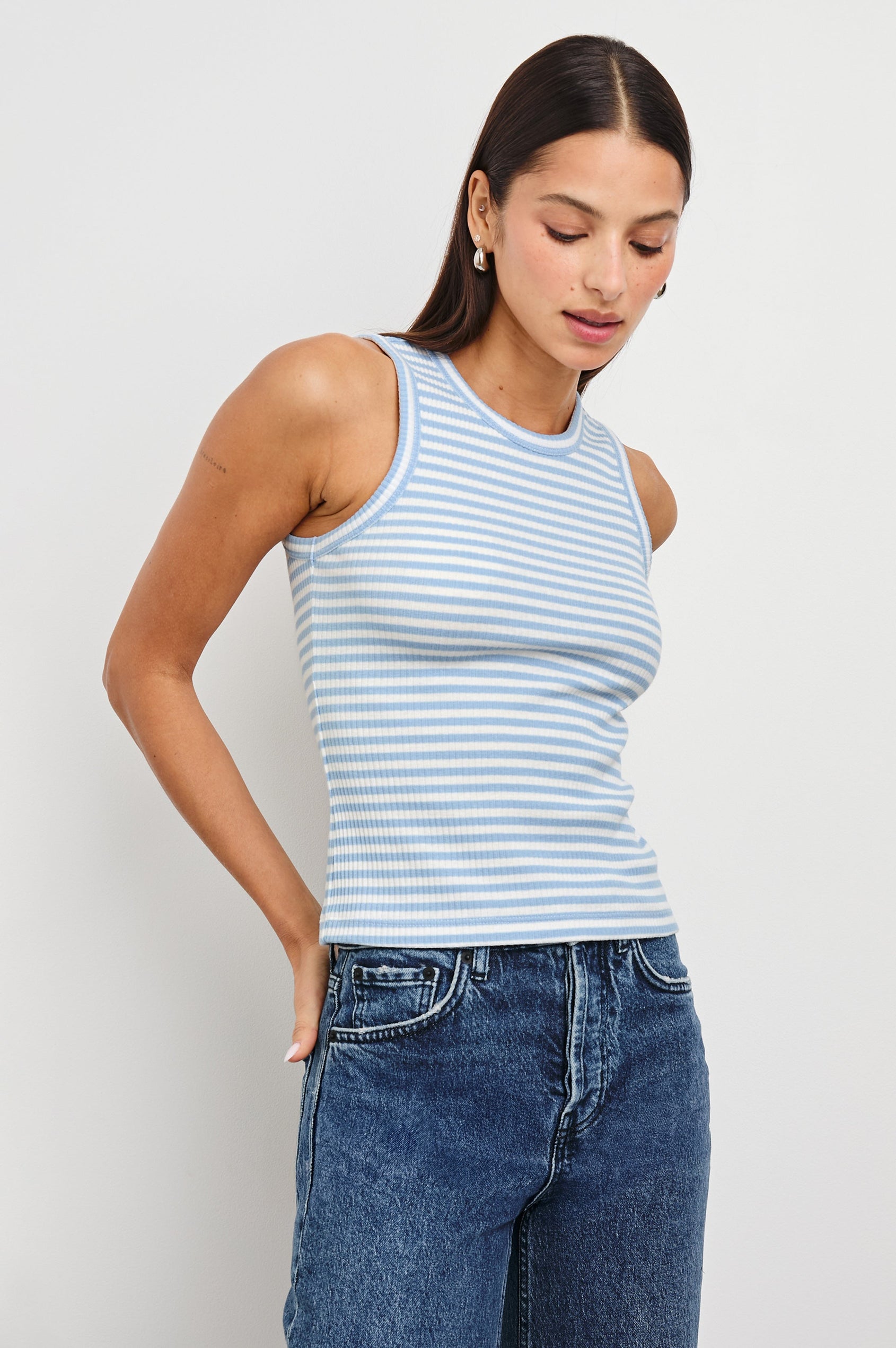 Fitted cotton Racerback Tank with Chambray Blue Stripes - front view on model looking down with hands in pocket