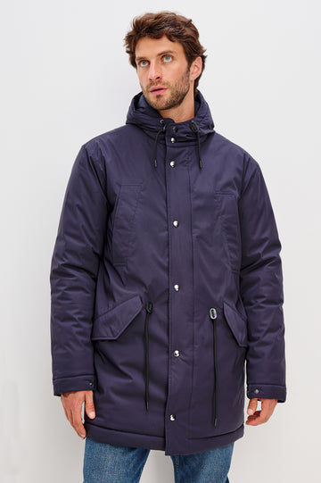 Rainier is a hooded parka coat, water-resistant and features hand warming pockets with snap closure, drawcord at hood and waist for sinching effect and a double flap center front closure and back seam vent in Navy colorway. Front view featured on model.