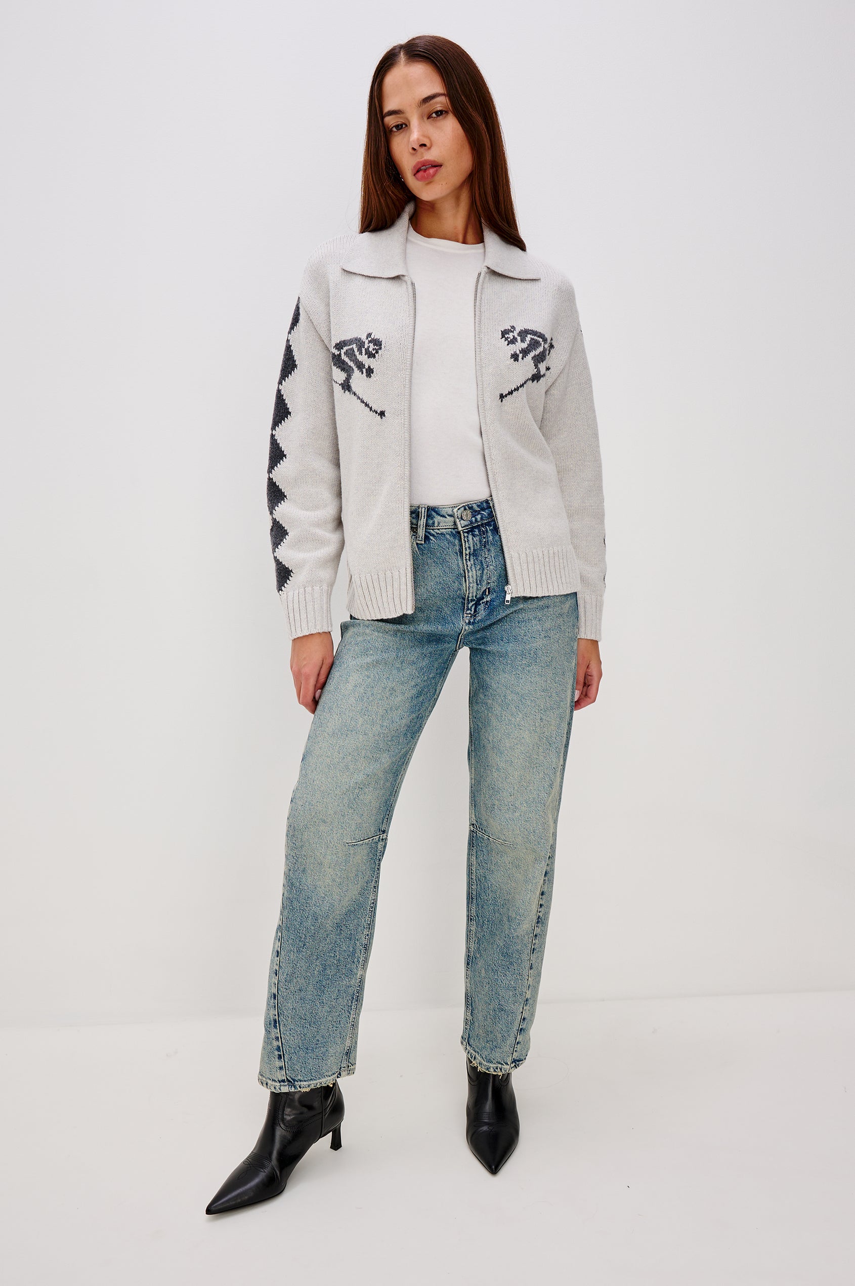 Rhea, a longline cardigan in a wool blend with skier motifs in Powder Grey Colorway. The cardigan has a relaxed fit and zip-front closure. Full Boldy Front View Featured on Model, Unzipped