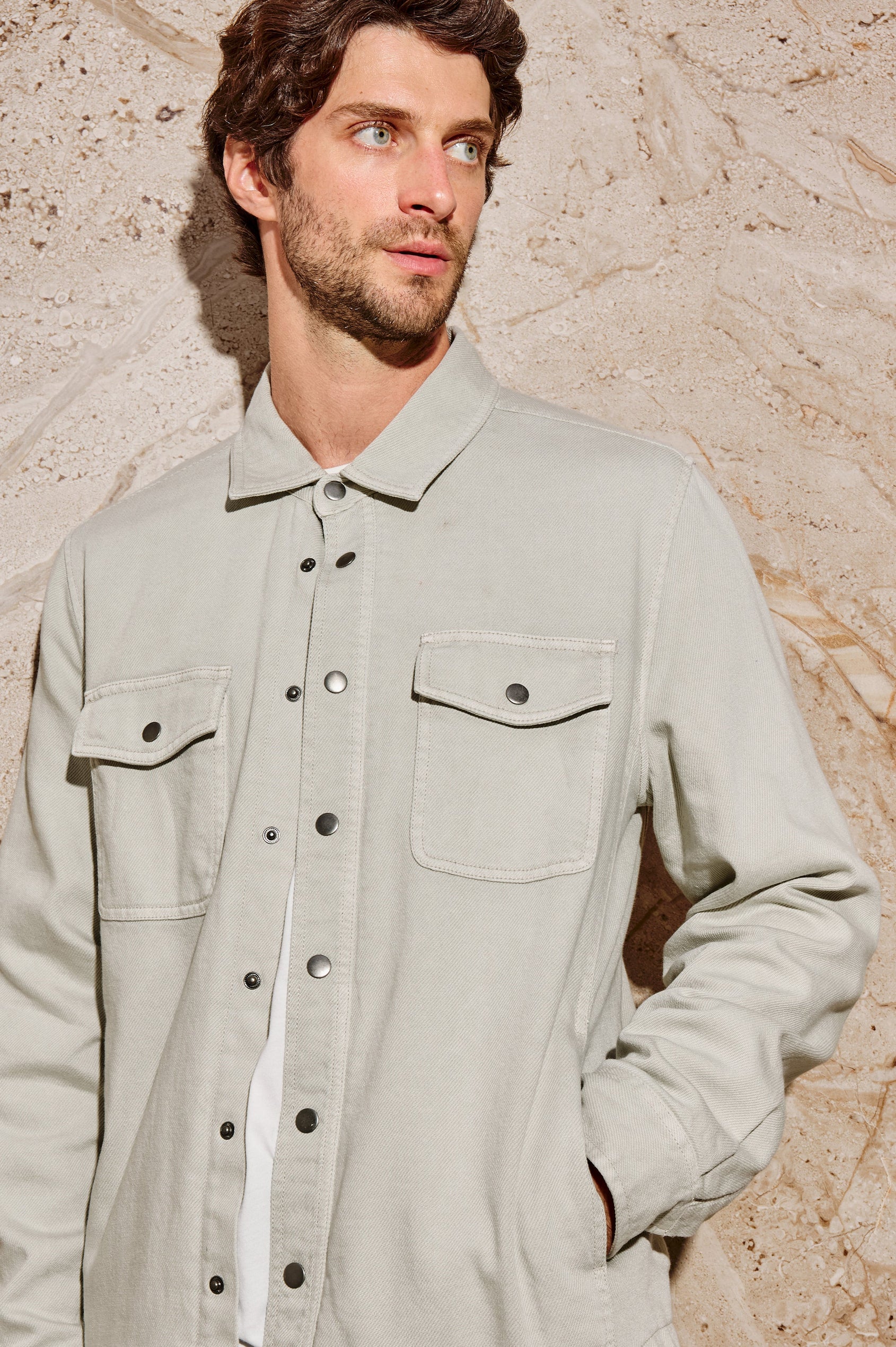 Rhett is a collared snap front shirt jacket with two chest pockets, side pockets and adjustable sleeve plackets in Stone colorway. Front detail view featured on model.
