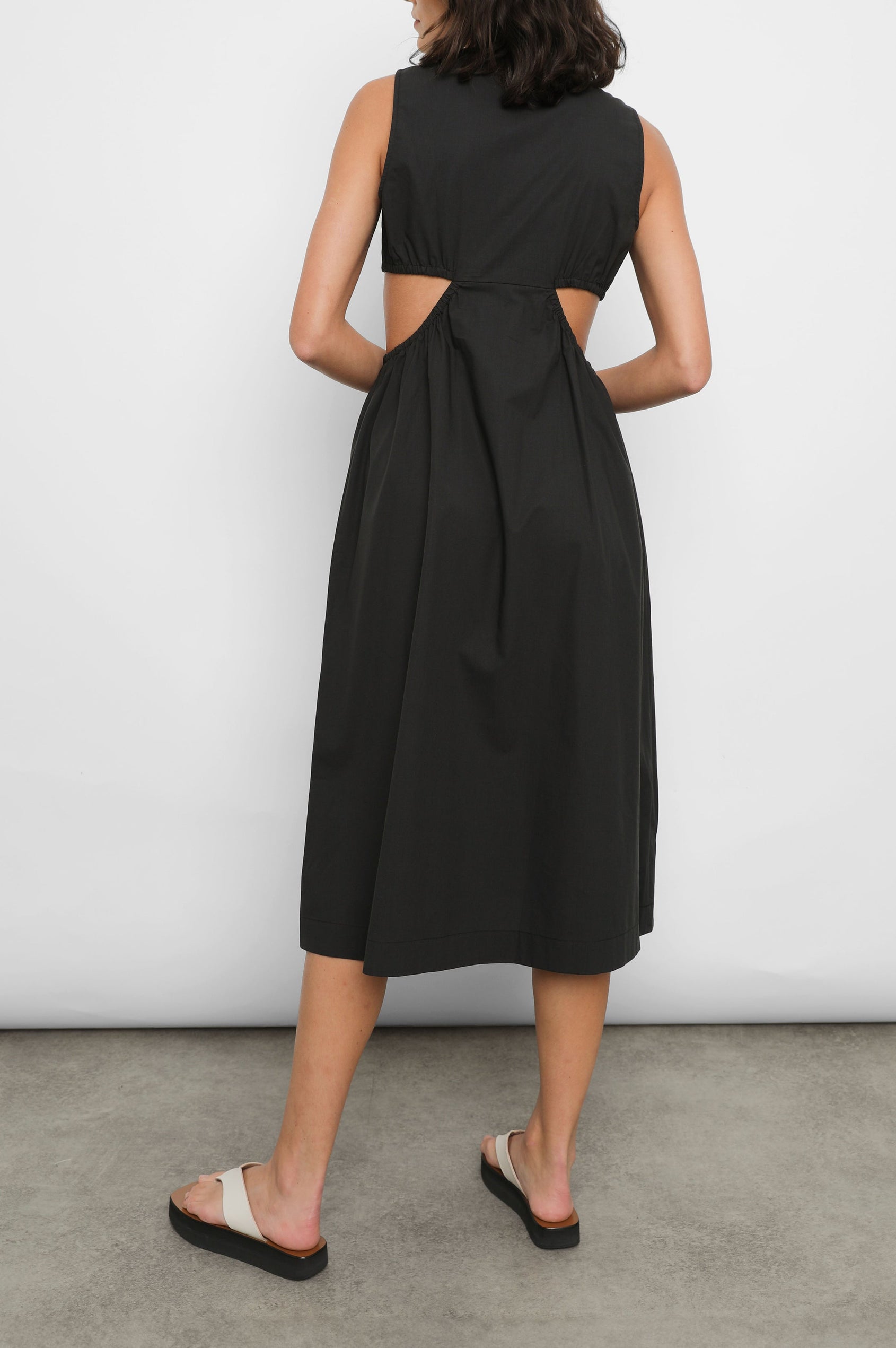 Rizo Sleeveless Midi Dress with Wide Shoulder Straps, a Deep V Neck with a Cutout, and Cutouts Beneath the Bust and Circling to the Back in Black Colorway - Back Full Body View Featured on Model  