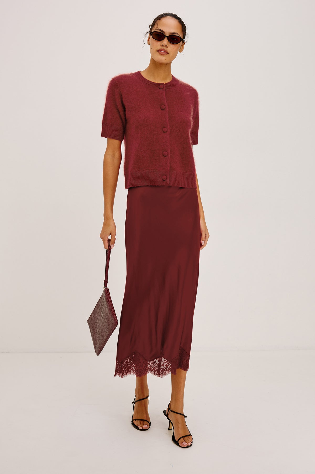 Ebony Midi Skirt Bias Cut in Satin With Clean Elastic Waistband, Pull-On Fit, and Tonal Lace Trim at Hem in Crimson Colorway - Full Body Front View Featured on Model
